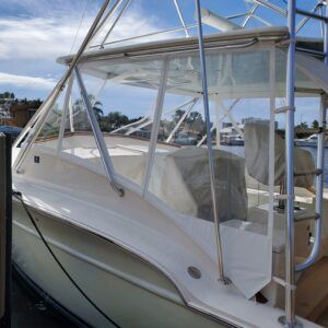A boat is docked at a dock with a clear cover on the windshield.