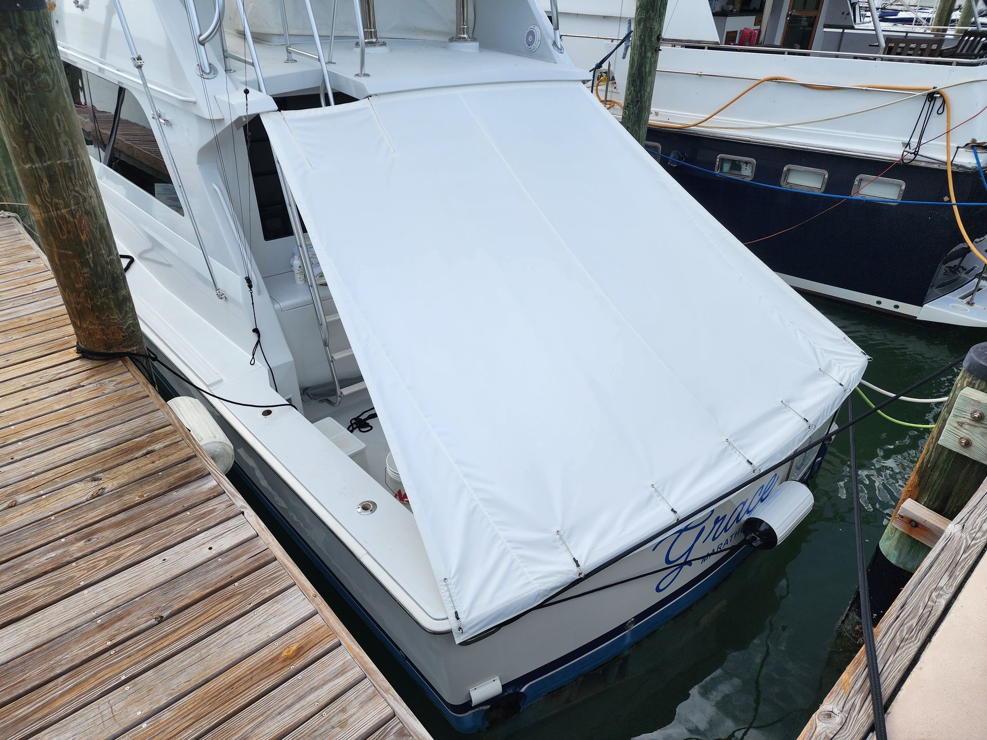A boat is docked at a dock with a white cover on it.
