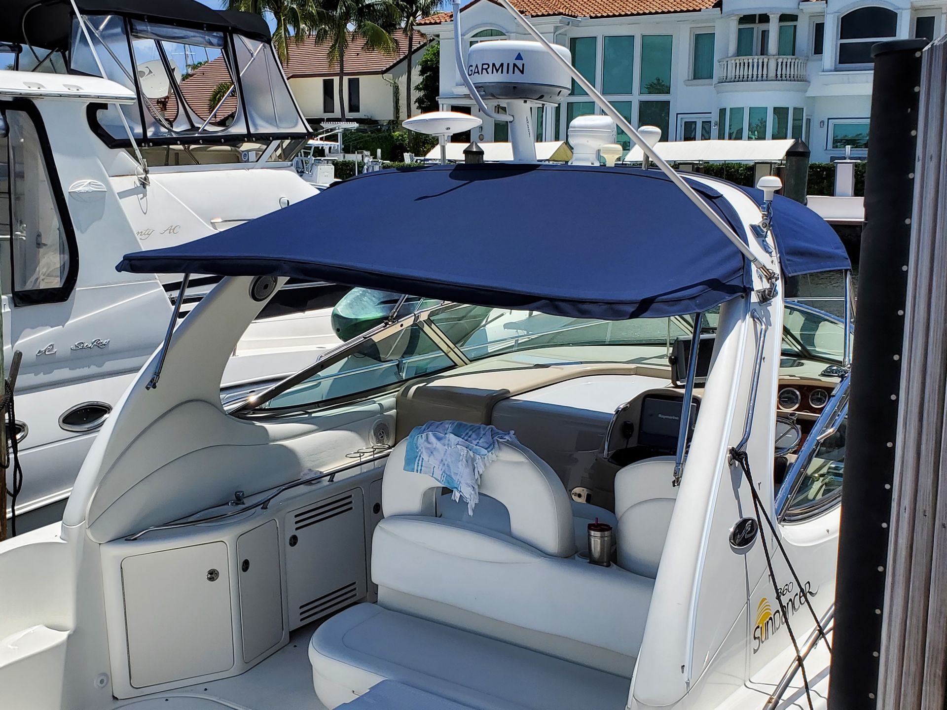 A white boat with a blue canopy is docked at a dock.