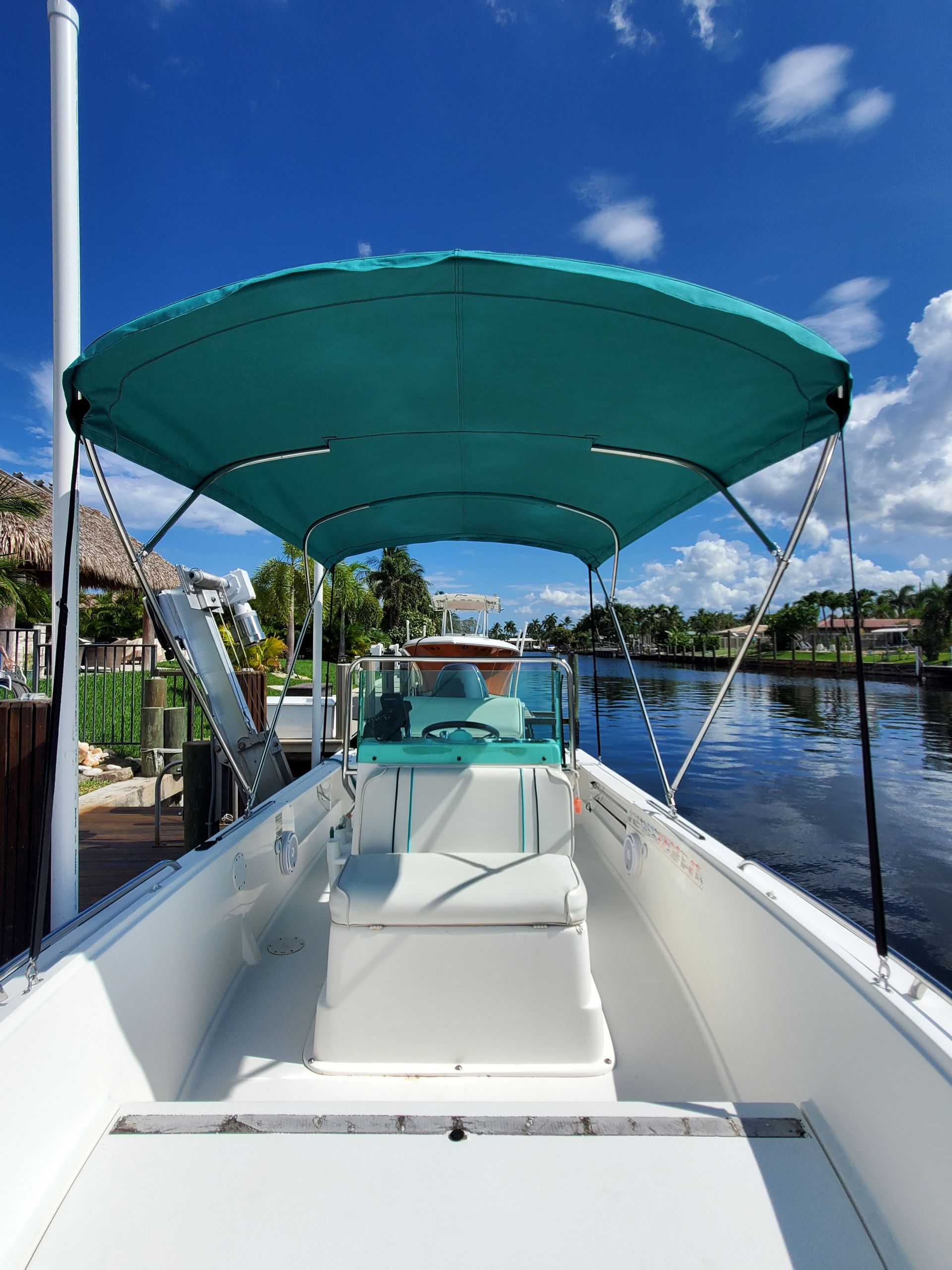 A white boat with a green canopy is docked in the water.