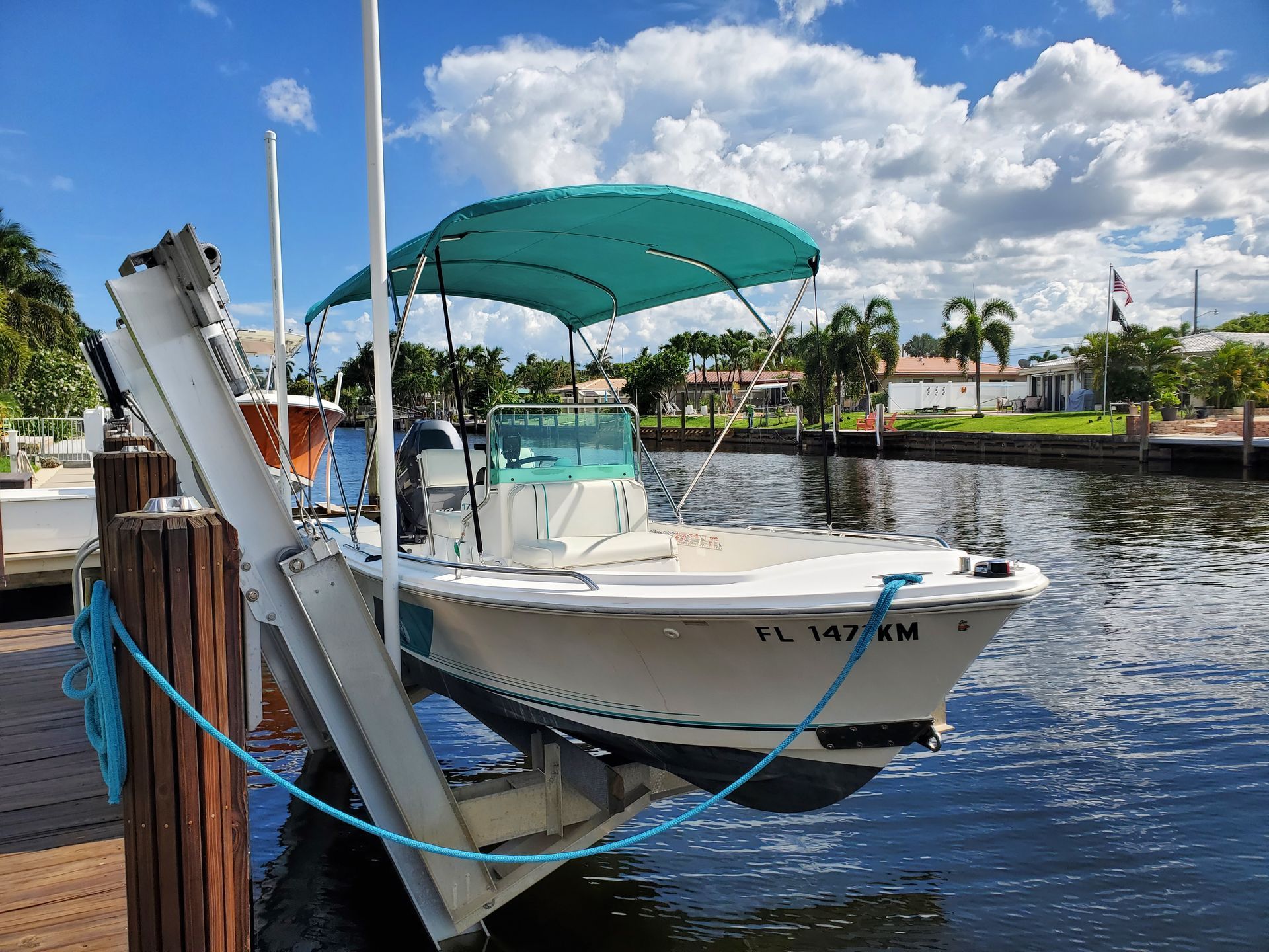 A white boat with a green canopy is docked at a dock.