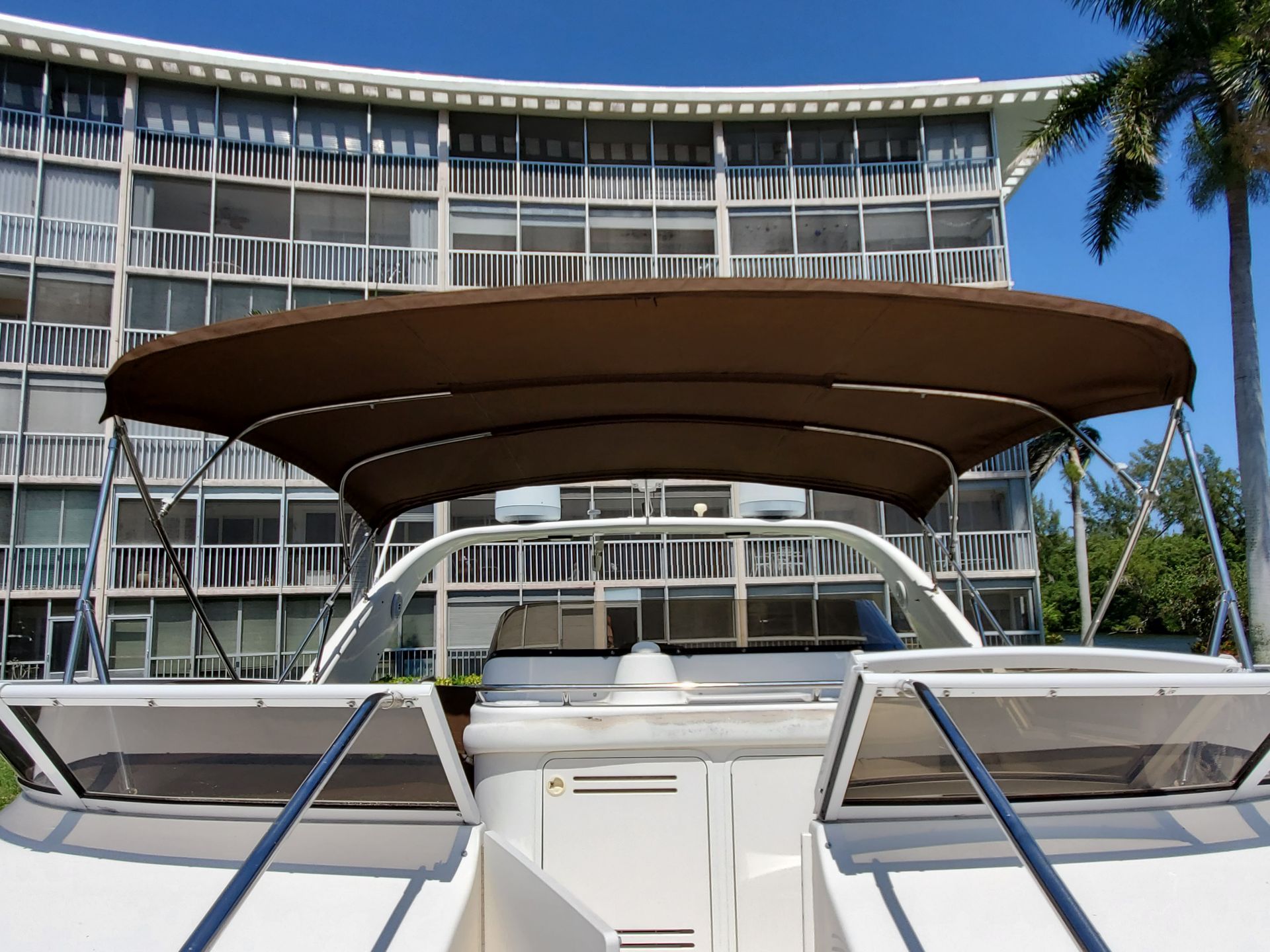 A boat with a brown canopy is parked in front of a building.