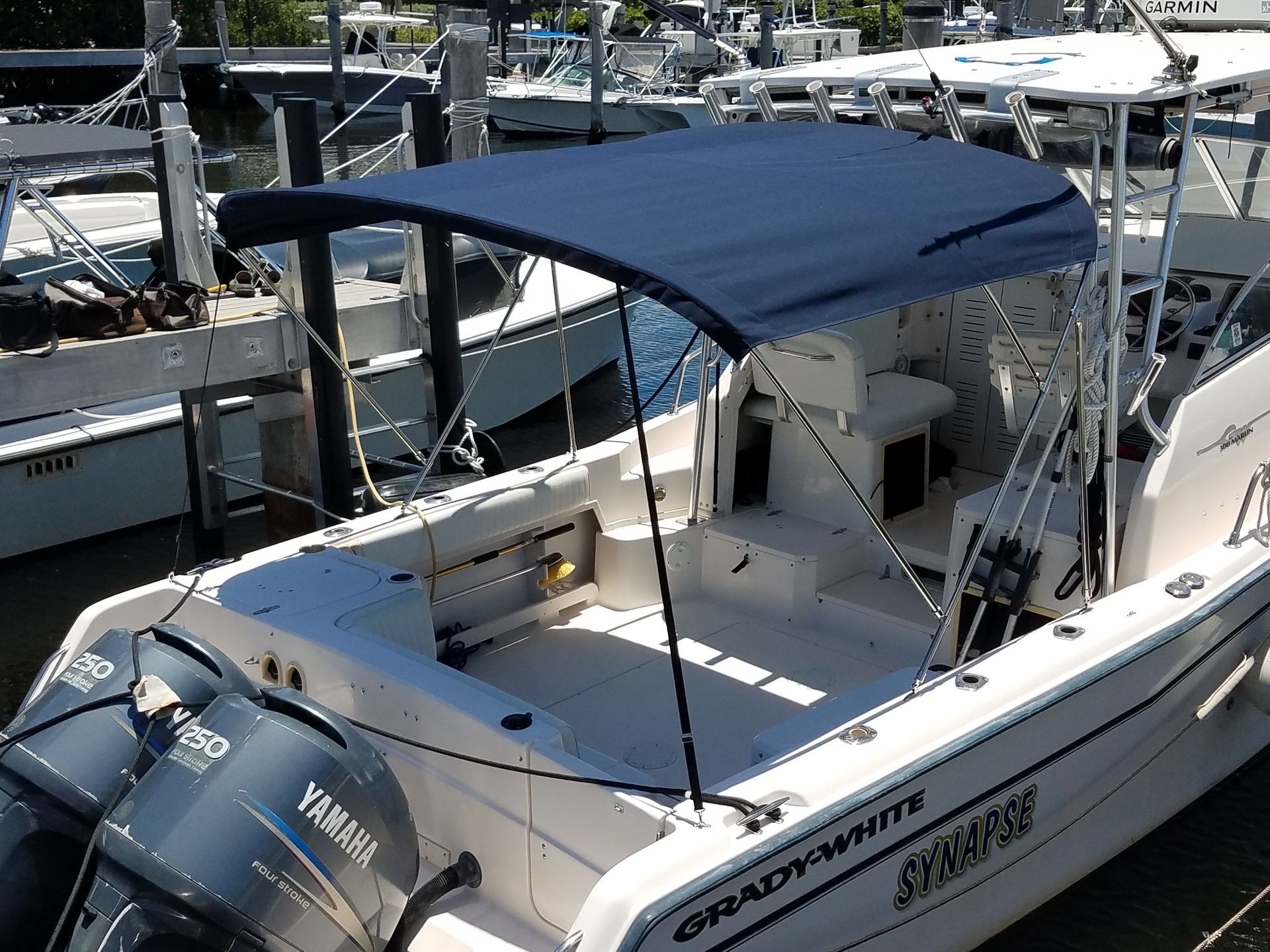 A white boat with a blue canopy is docked at a marina
