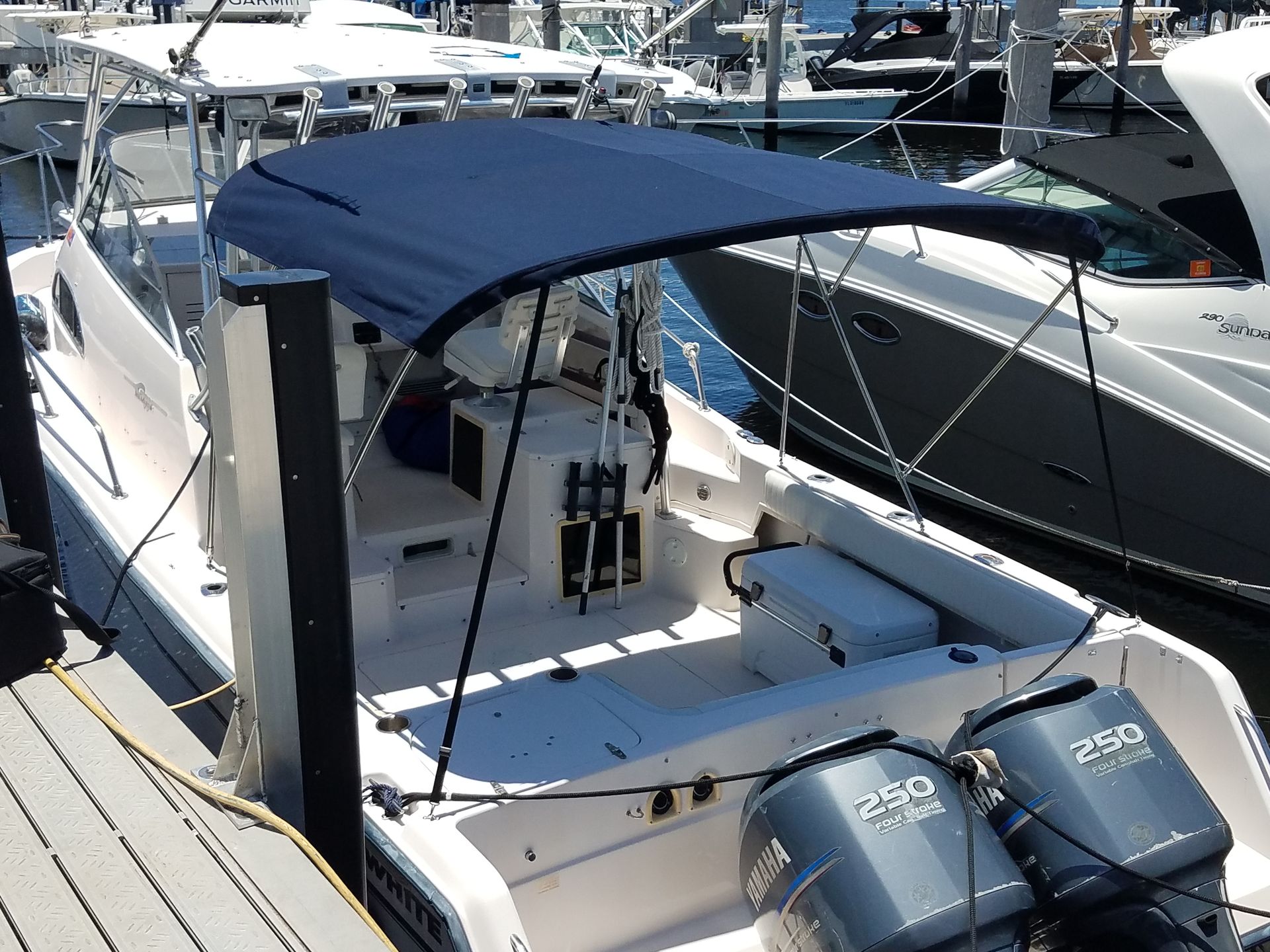A boat with a blue canopy is docked at a marina