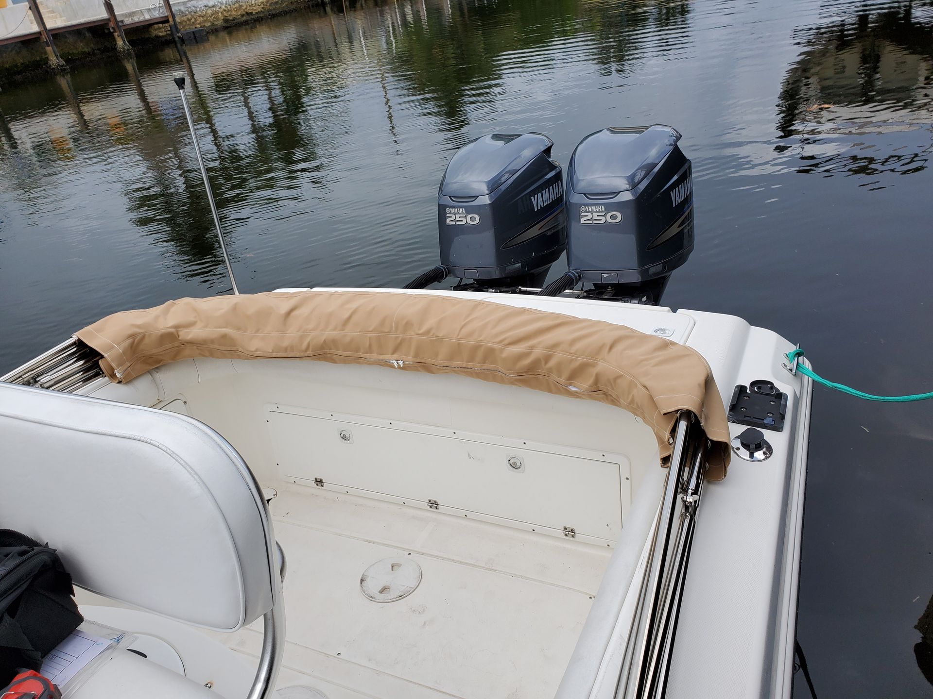 A white boat with two outboards is docked in the water.