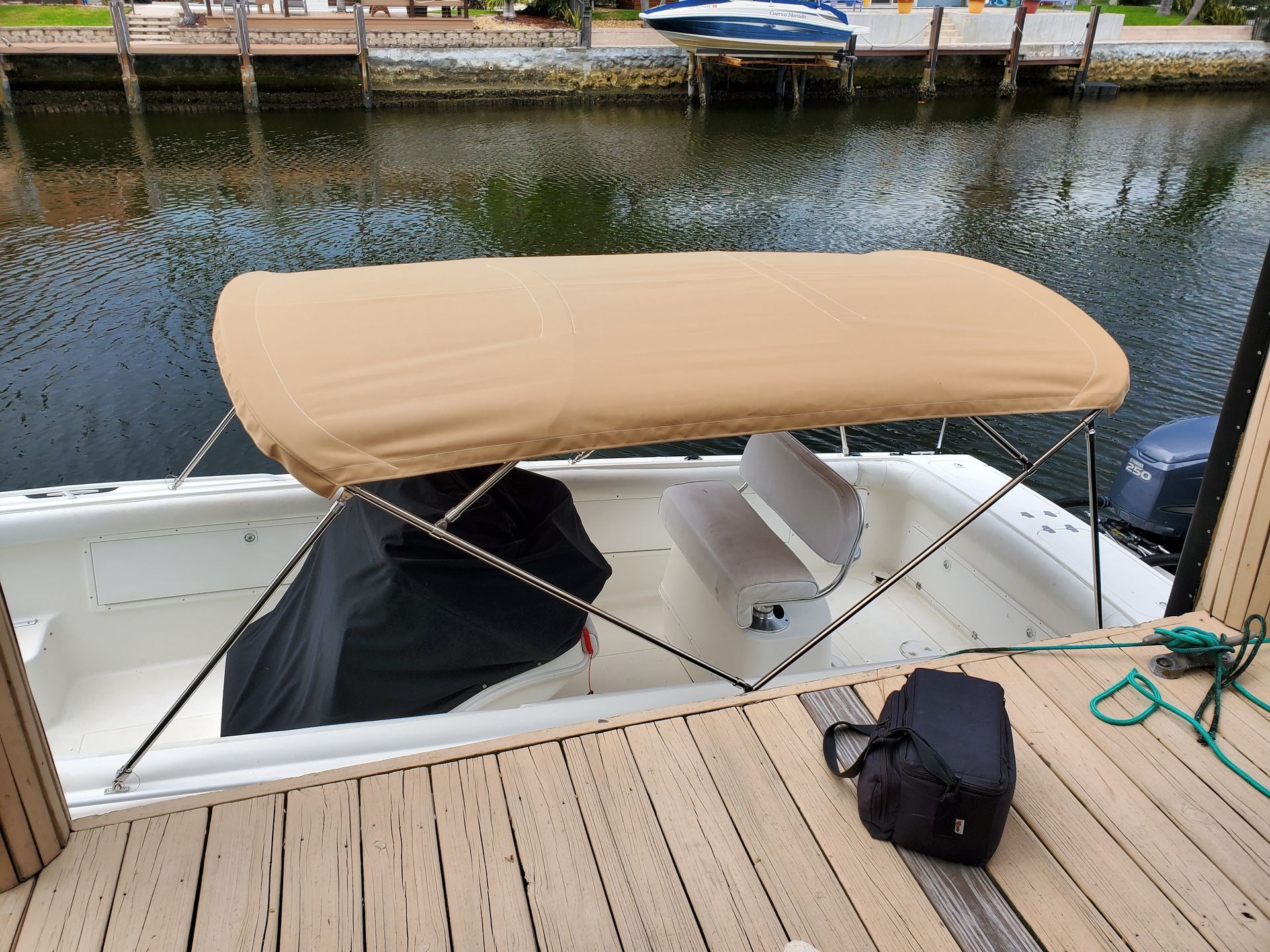A boat with a canopy is sitting on a dock next to a body of water.