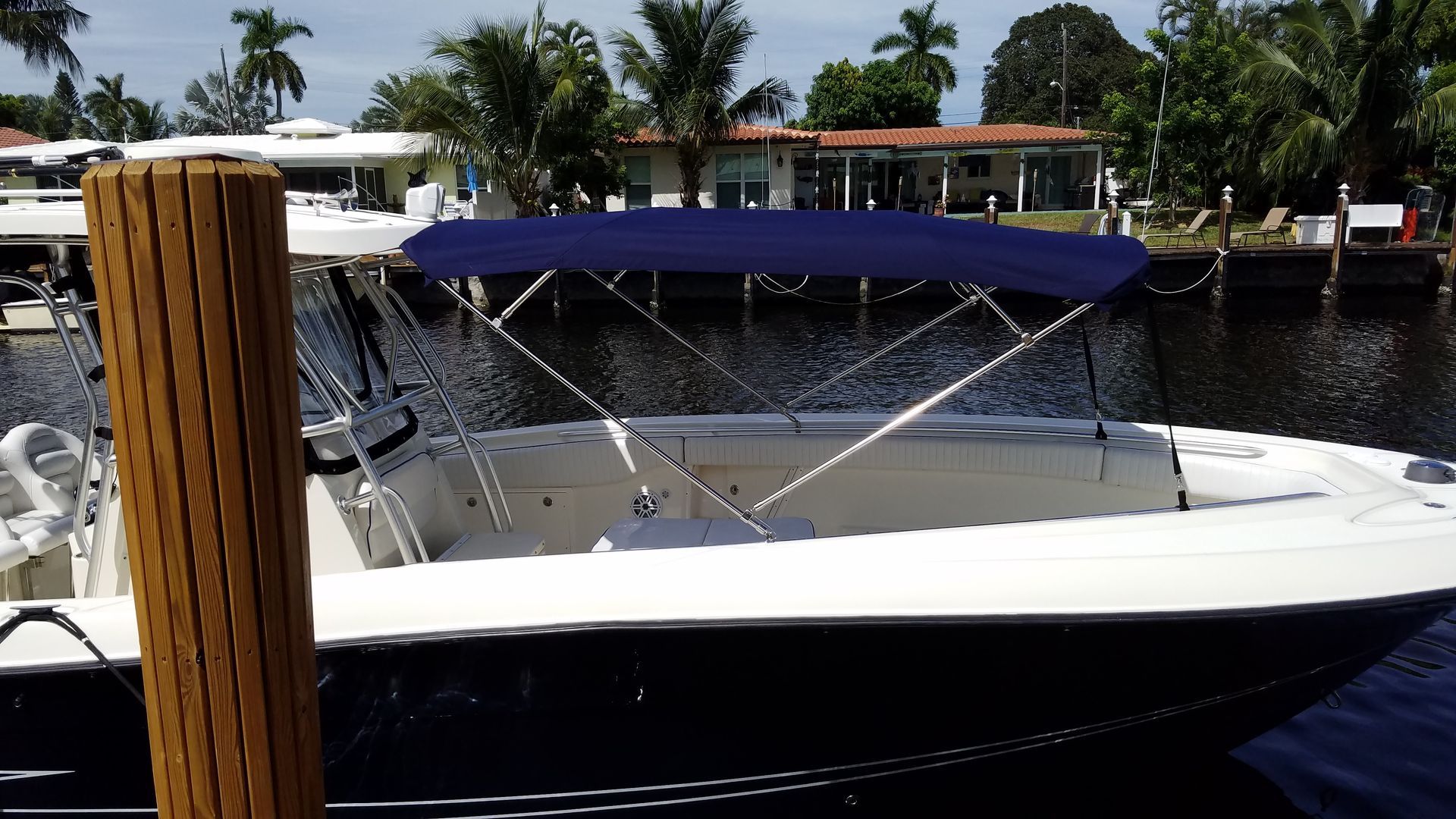 A boat with a blue canopy is docked at a dock