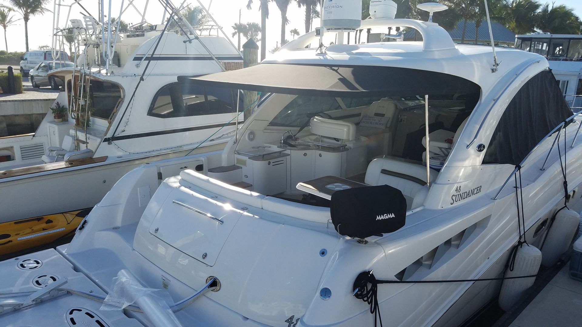 A white yacht is docked in a marina with other boats