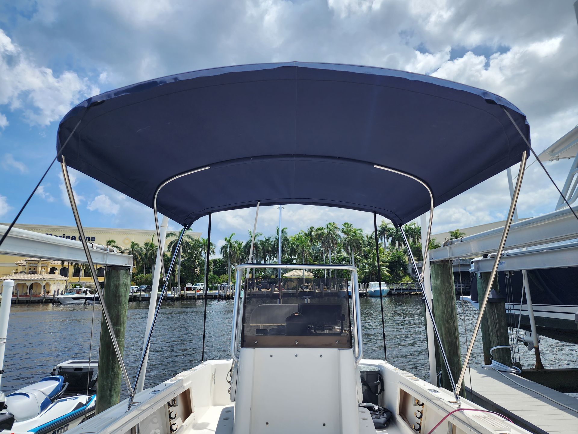 A boat with a blue canopy is docked at a marina.