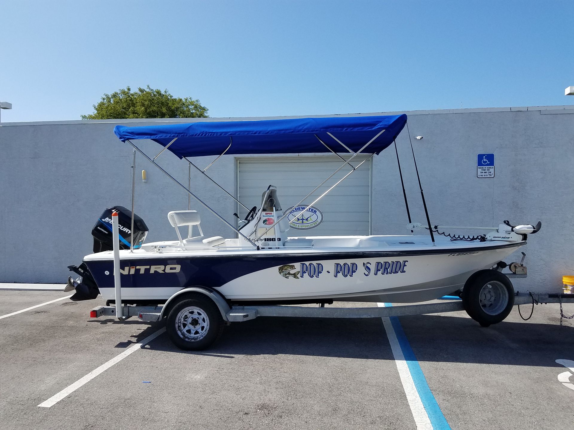 A boat with a blue canopy is parked in a parking lot