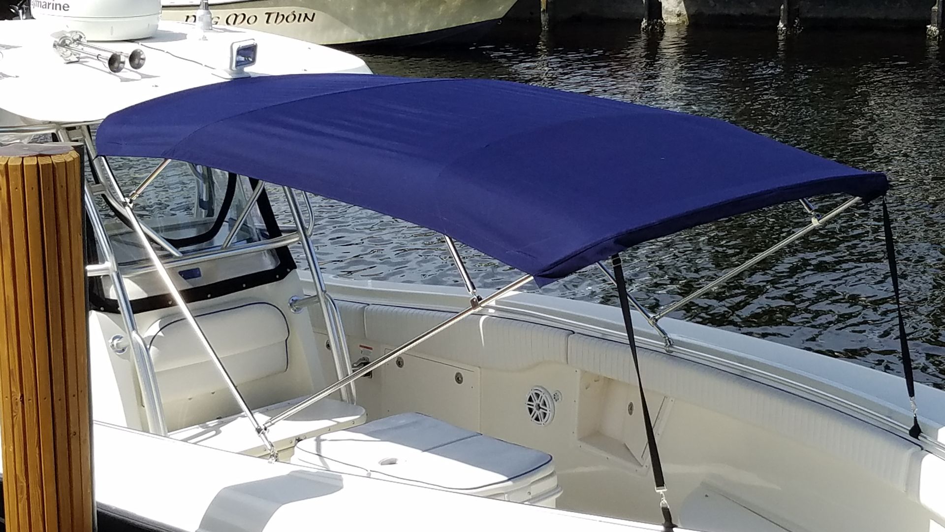 A boat with a blue canopy is docked in the water