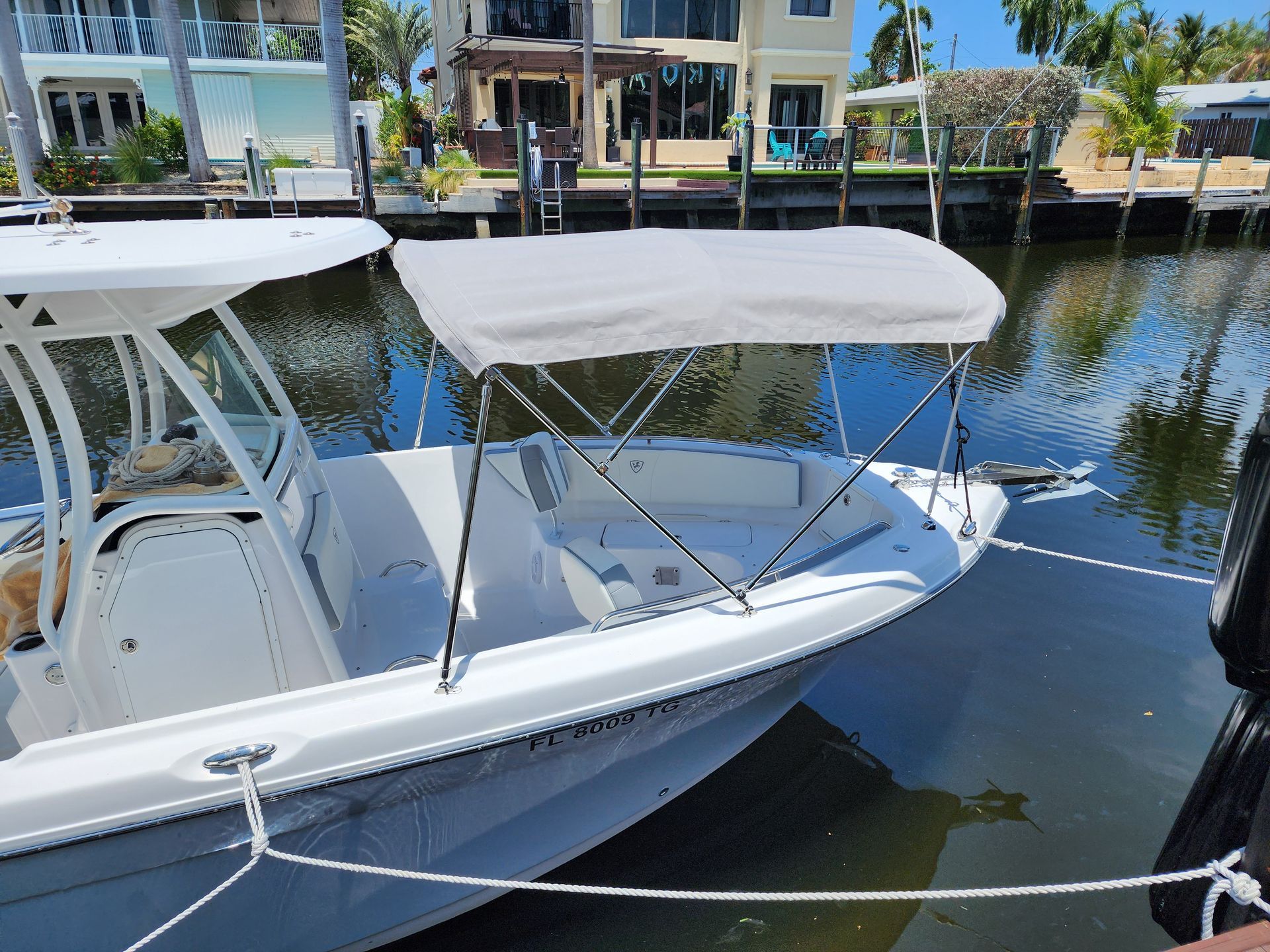 A white boat with a canopy is docked in the water