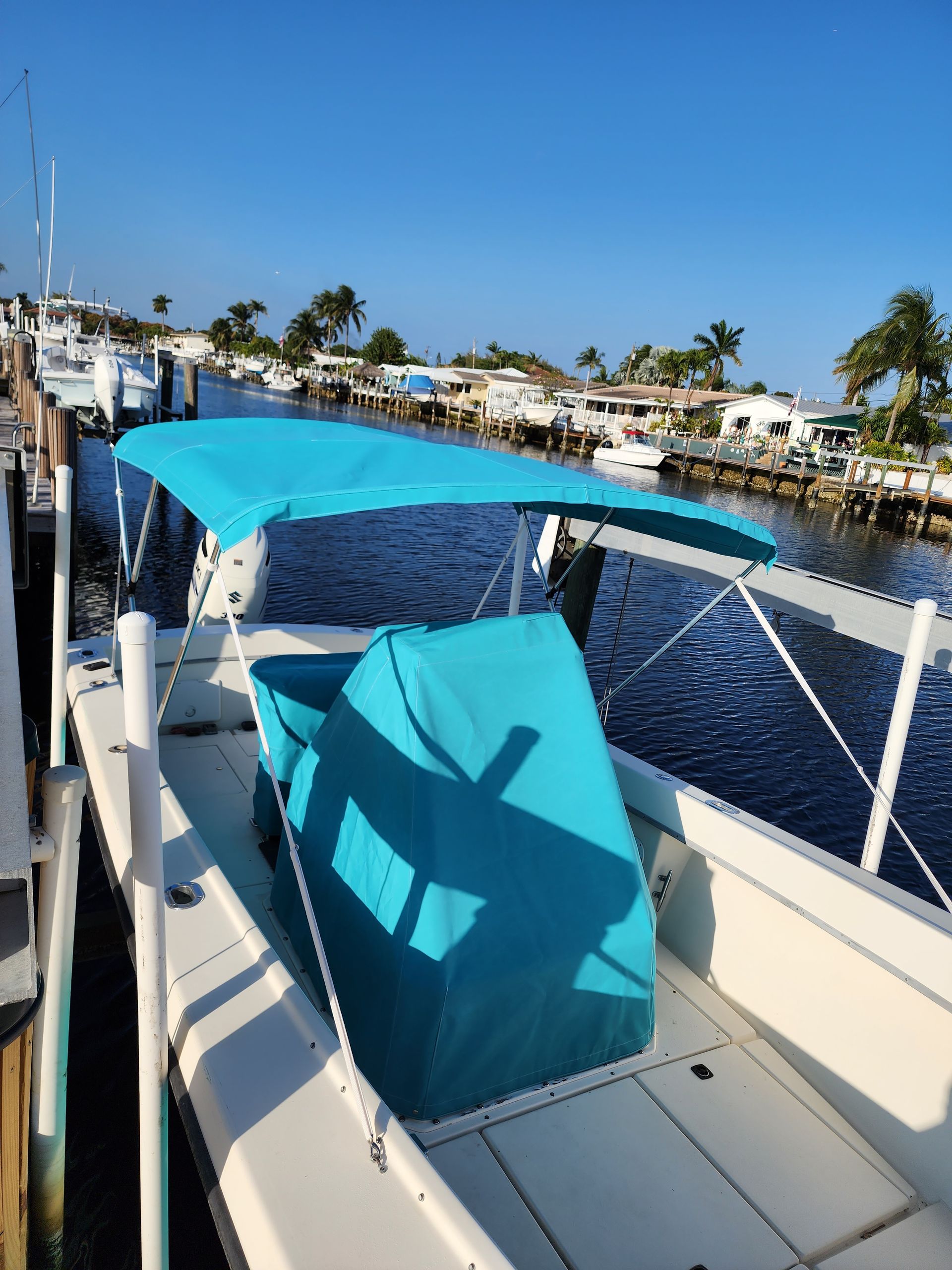 A boat with a blue canopy is docked at a dock