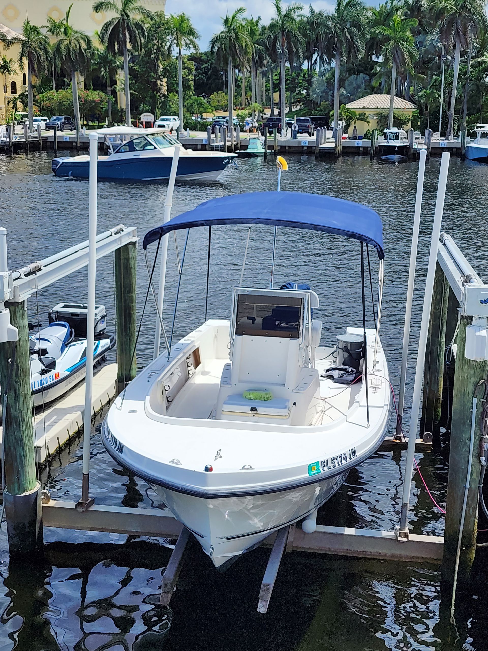 A white boat with a blue canopy is docked at a dock.