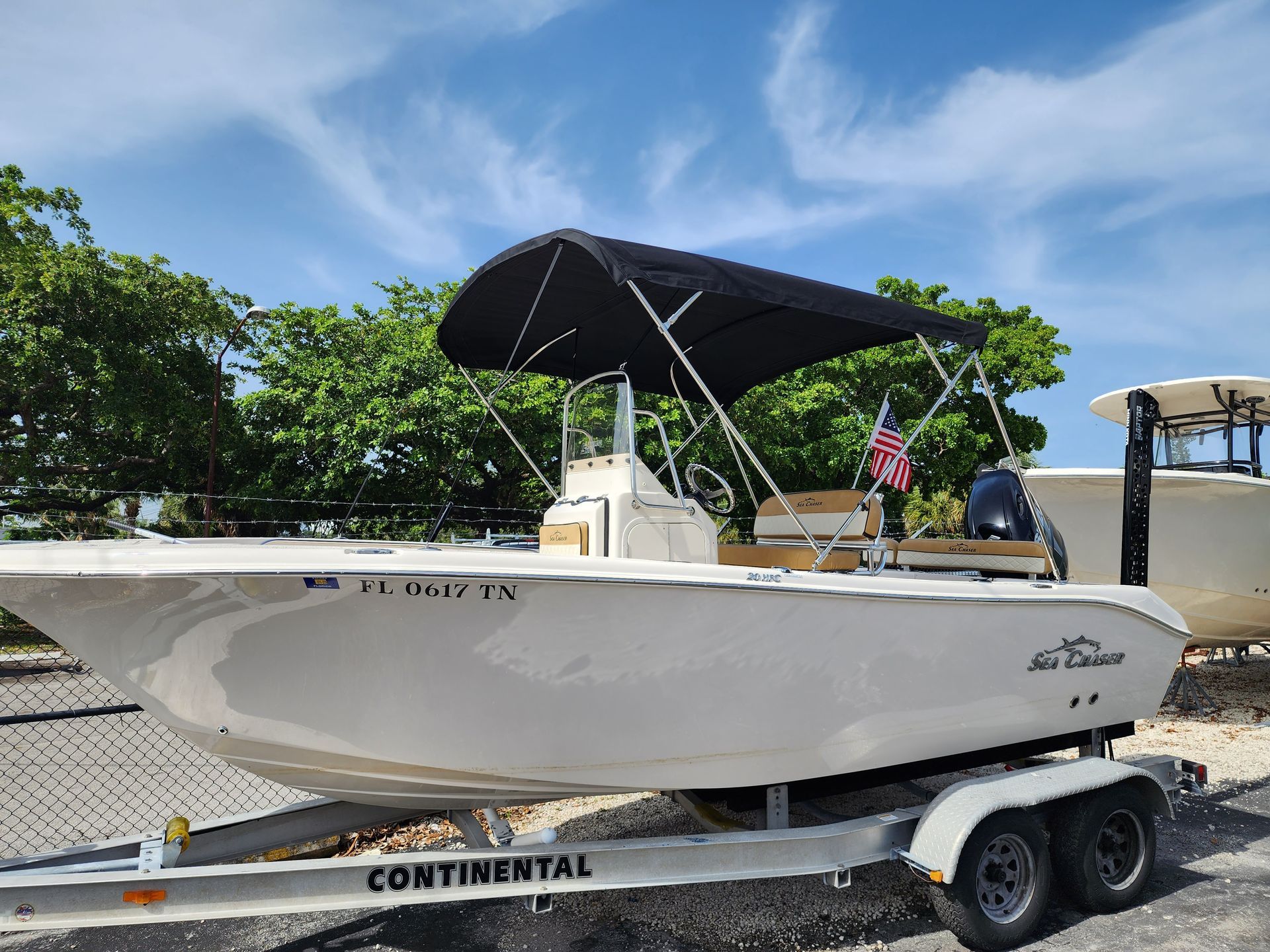 A white boat with a black canopy is parked on a trailer.