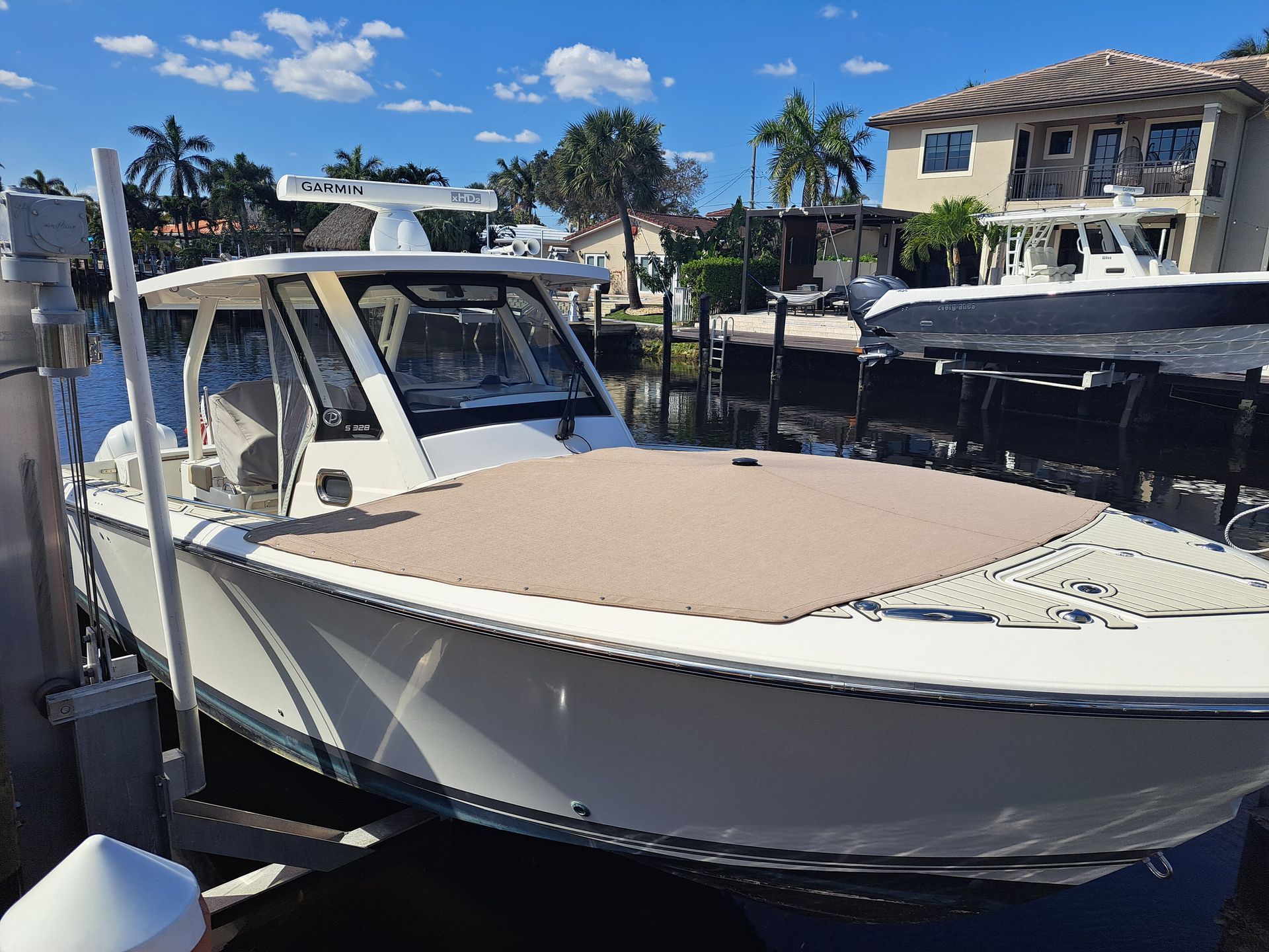 A white boat is docked in a marina next to a house