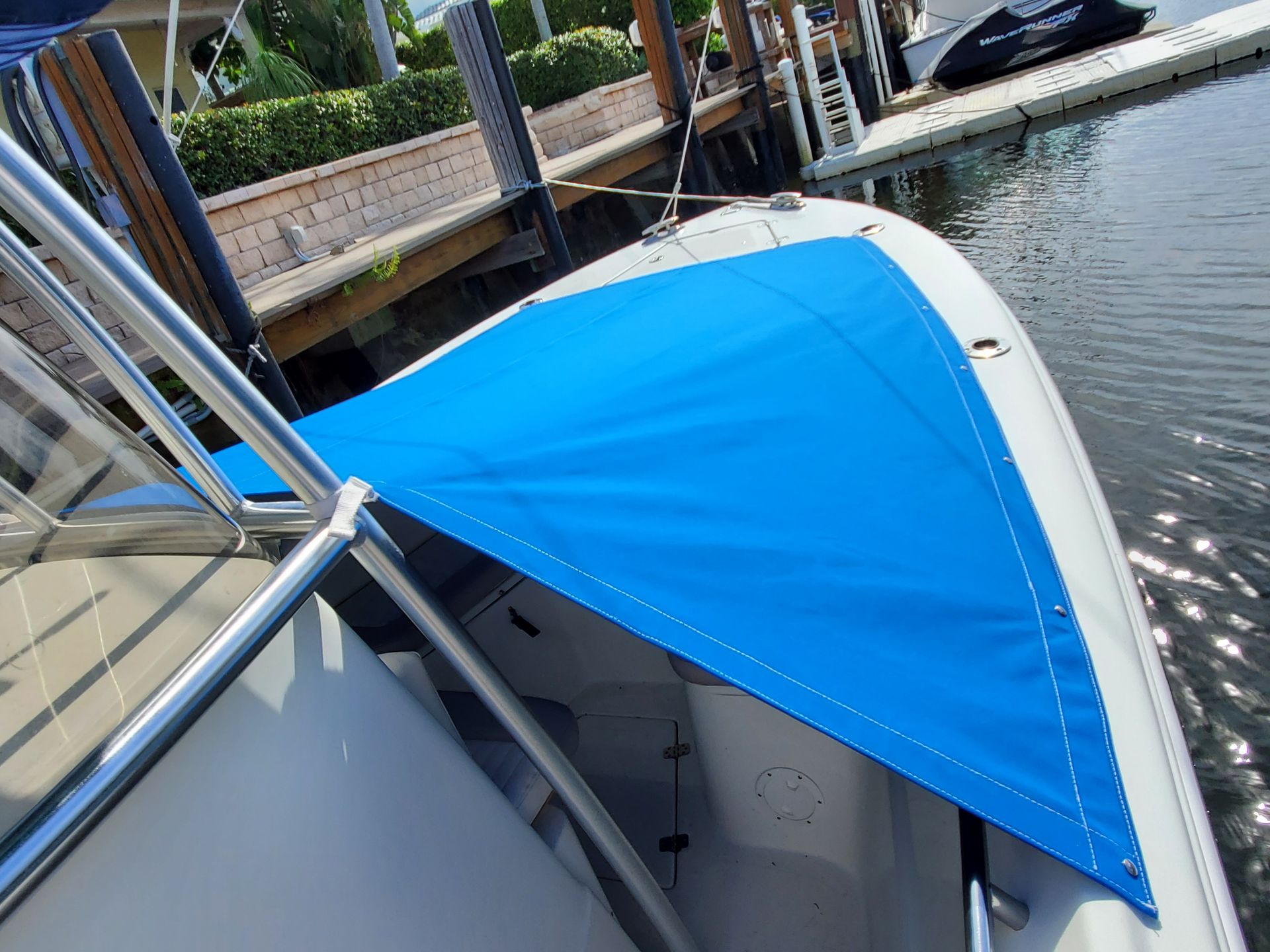 A boat with a blue canopy is docked at a dock.