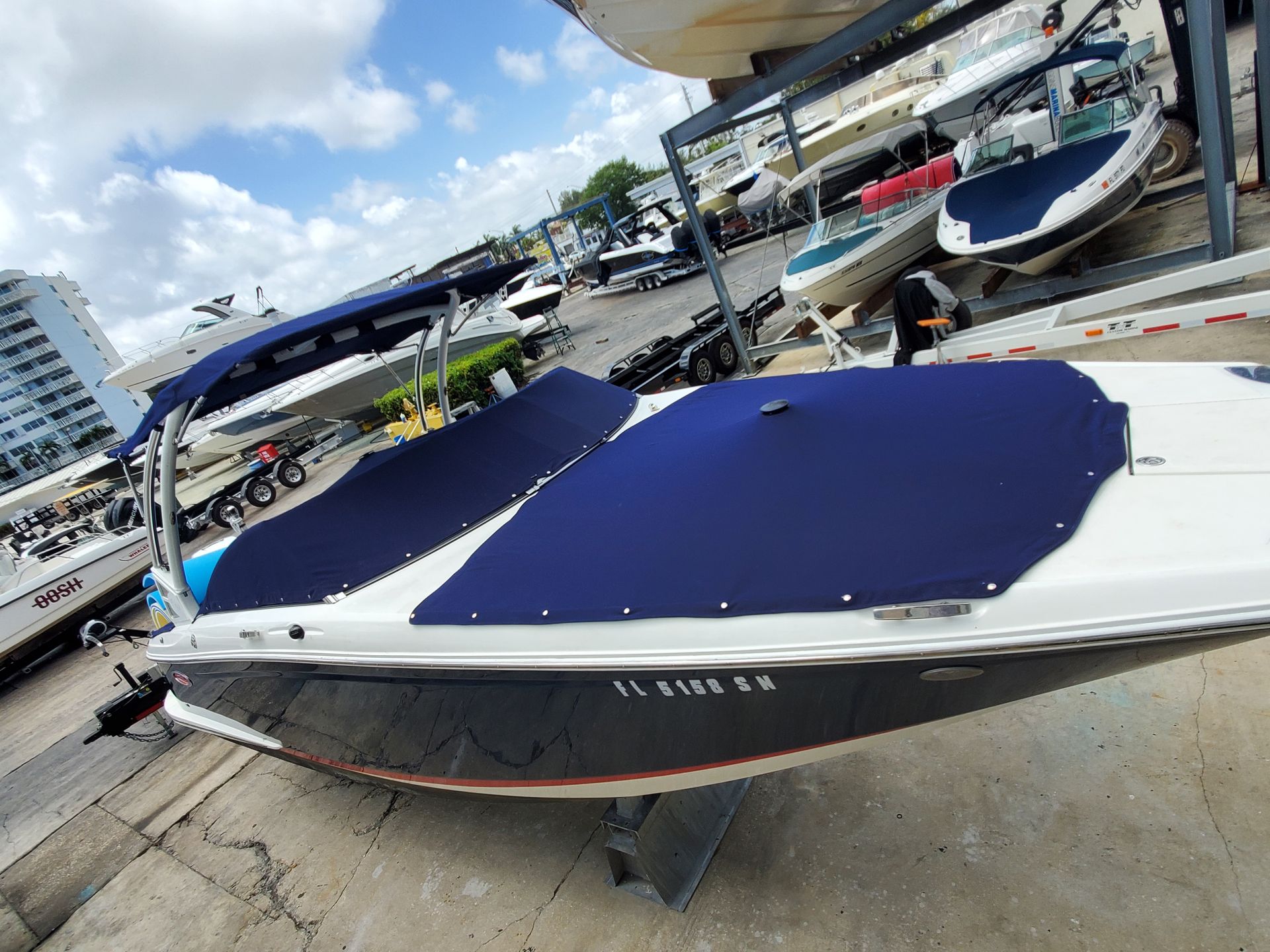 A boat with a blue cover is sitting on the ground in a marina.