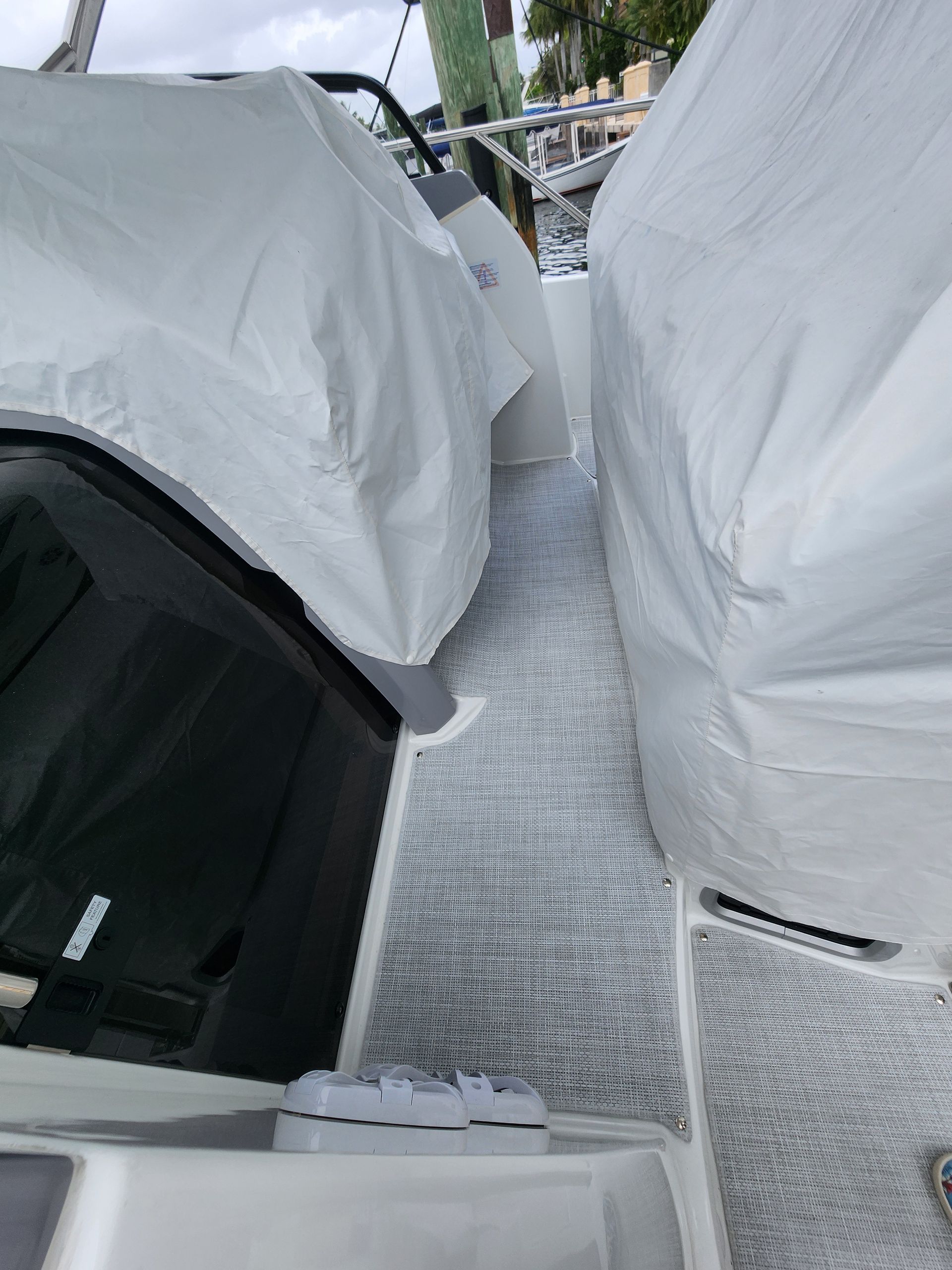 A boat with a white cover on it is parked next to another boat.