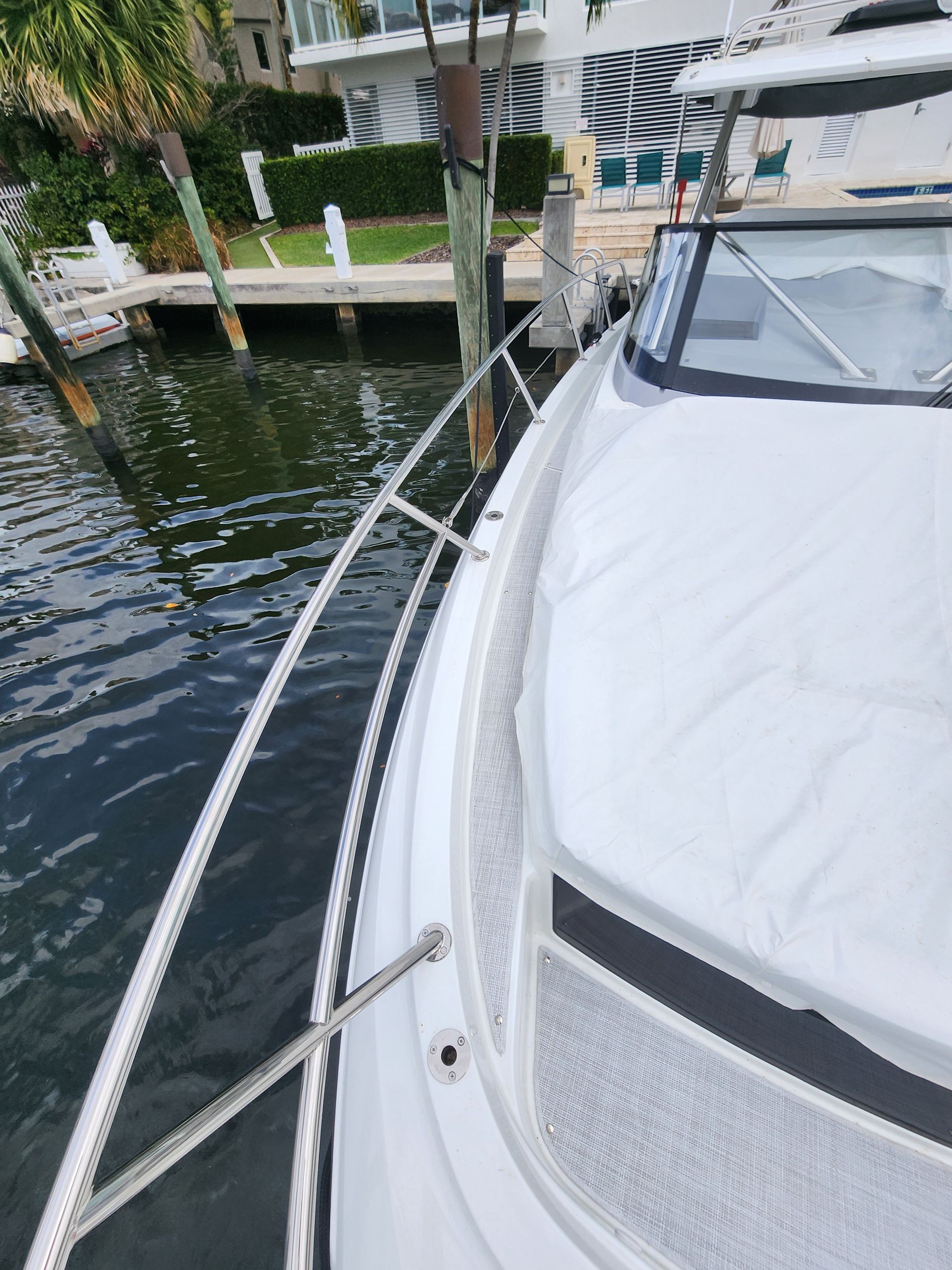 A white boat is docked in the water near a dock.