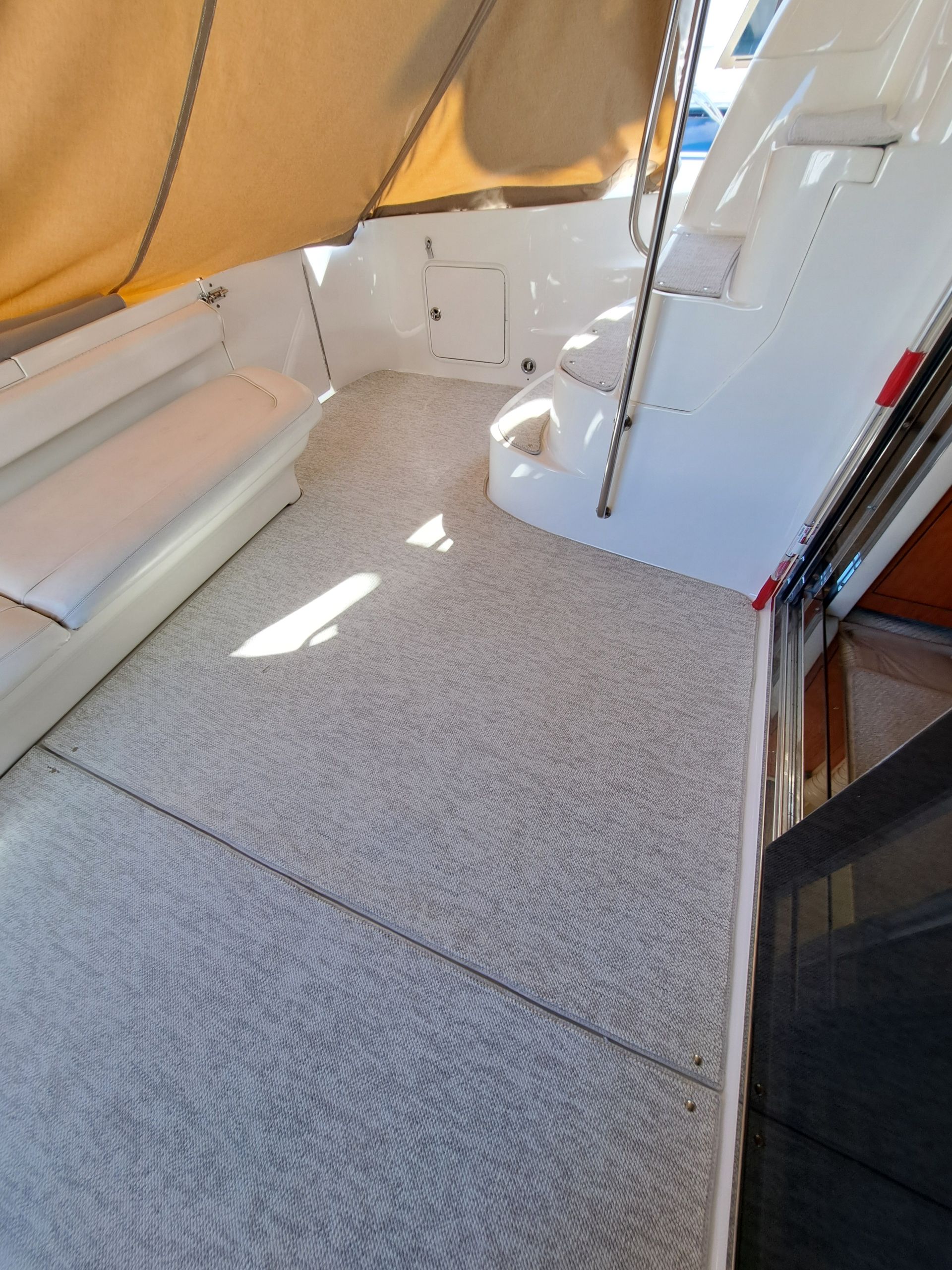The inside of a boat with a carpeted floor and a yellow awning.