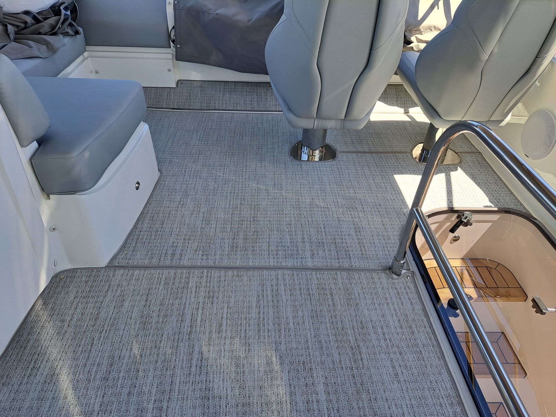 The inside of a boat with a carpeted floor and seats.