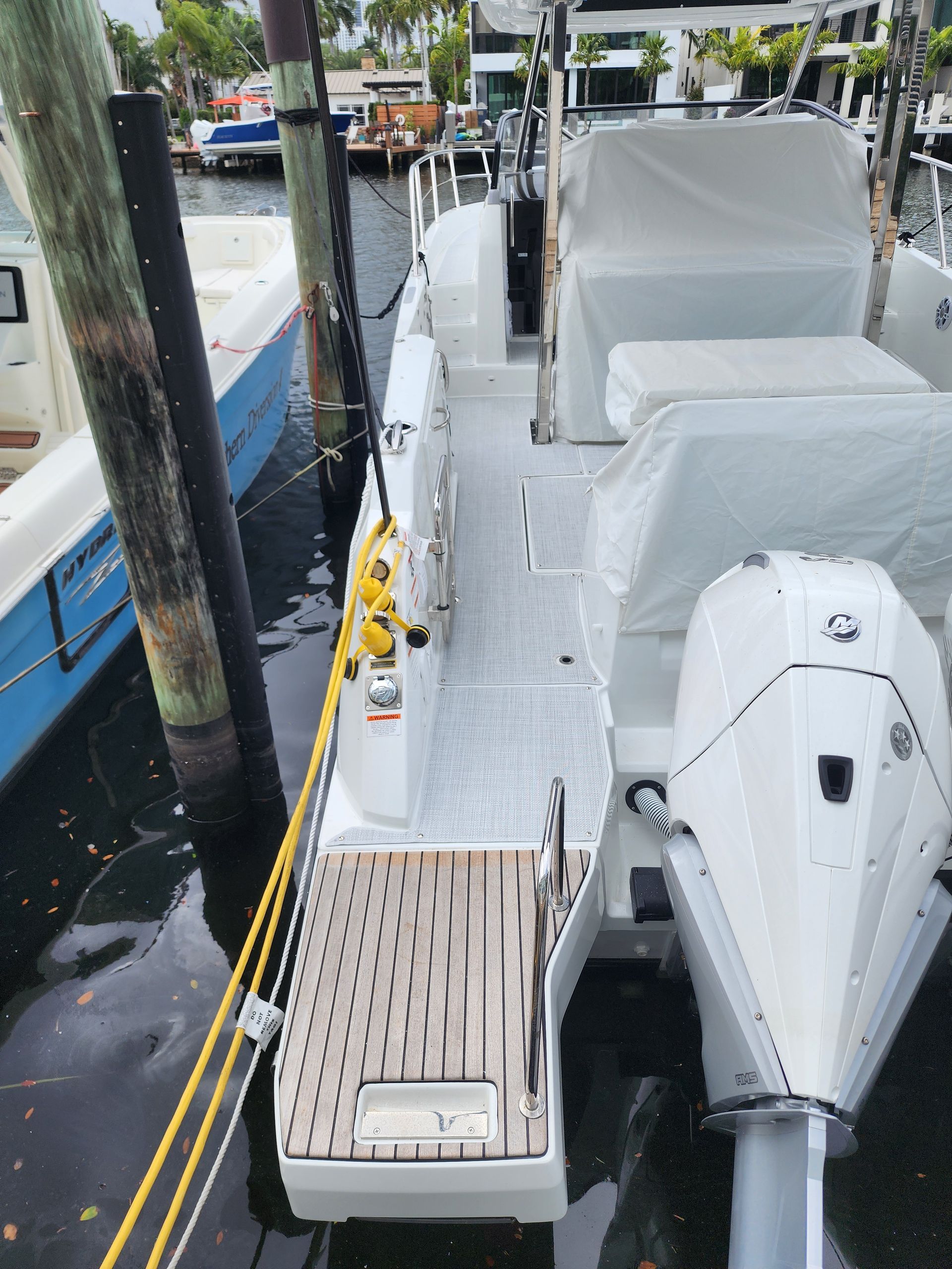 A white boat is docked next to a blue boat