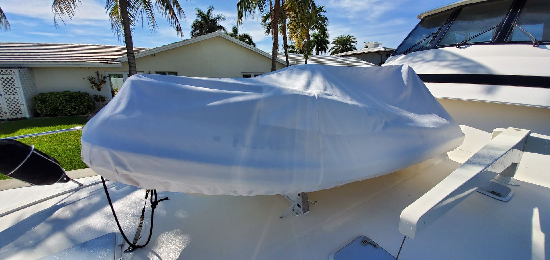 A boat with a cover on it is sitting in front of a house.