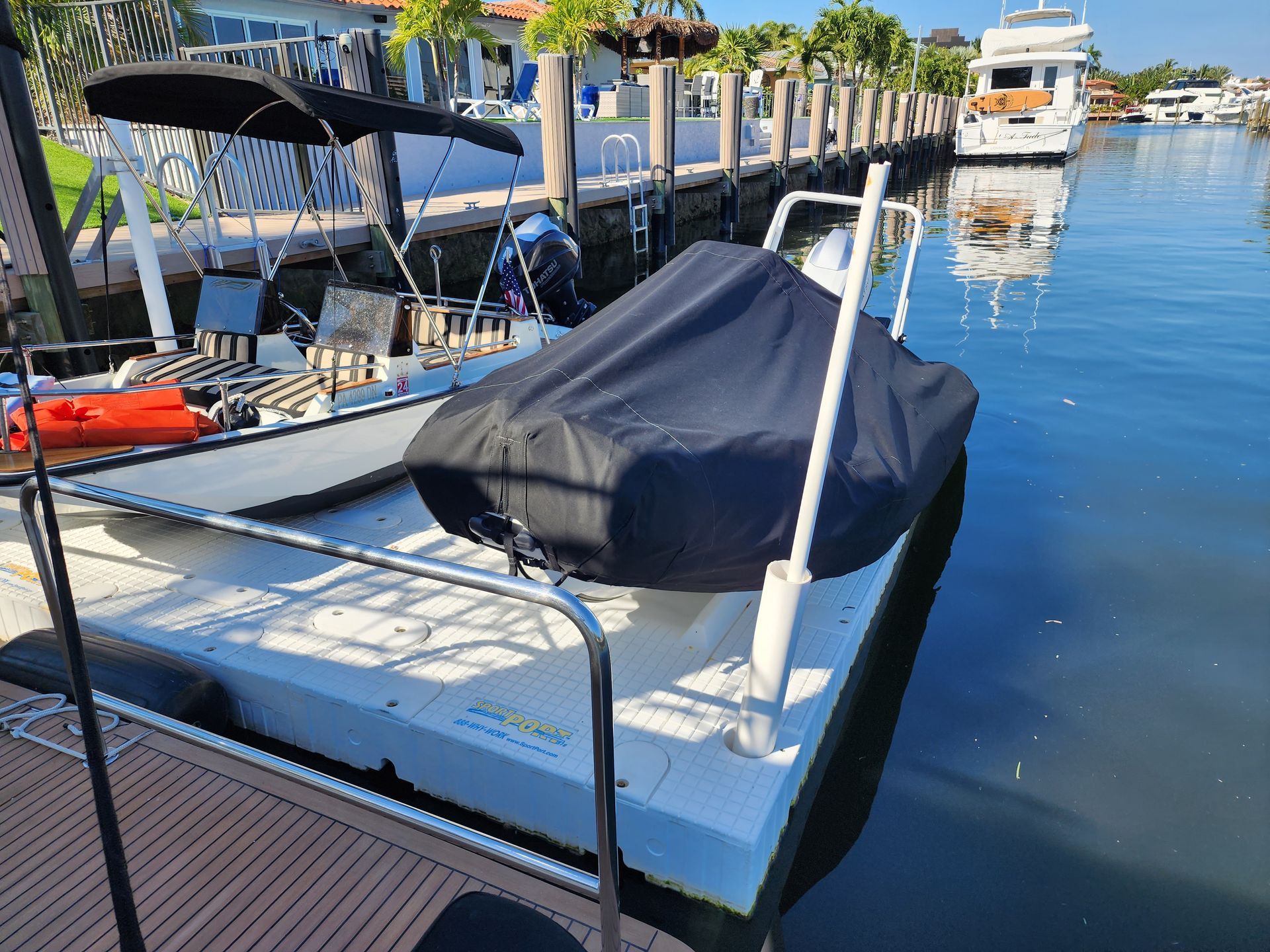 A boat with a black cover on it is docked at a dock.