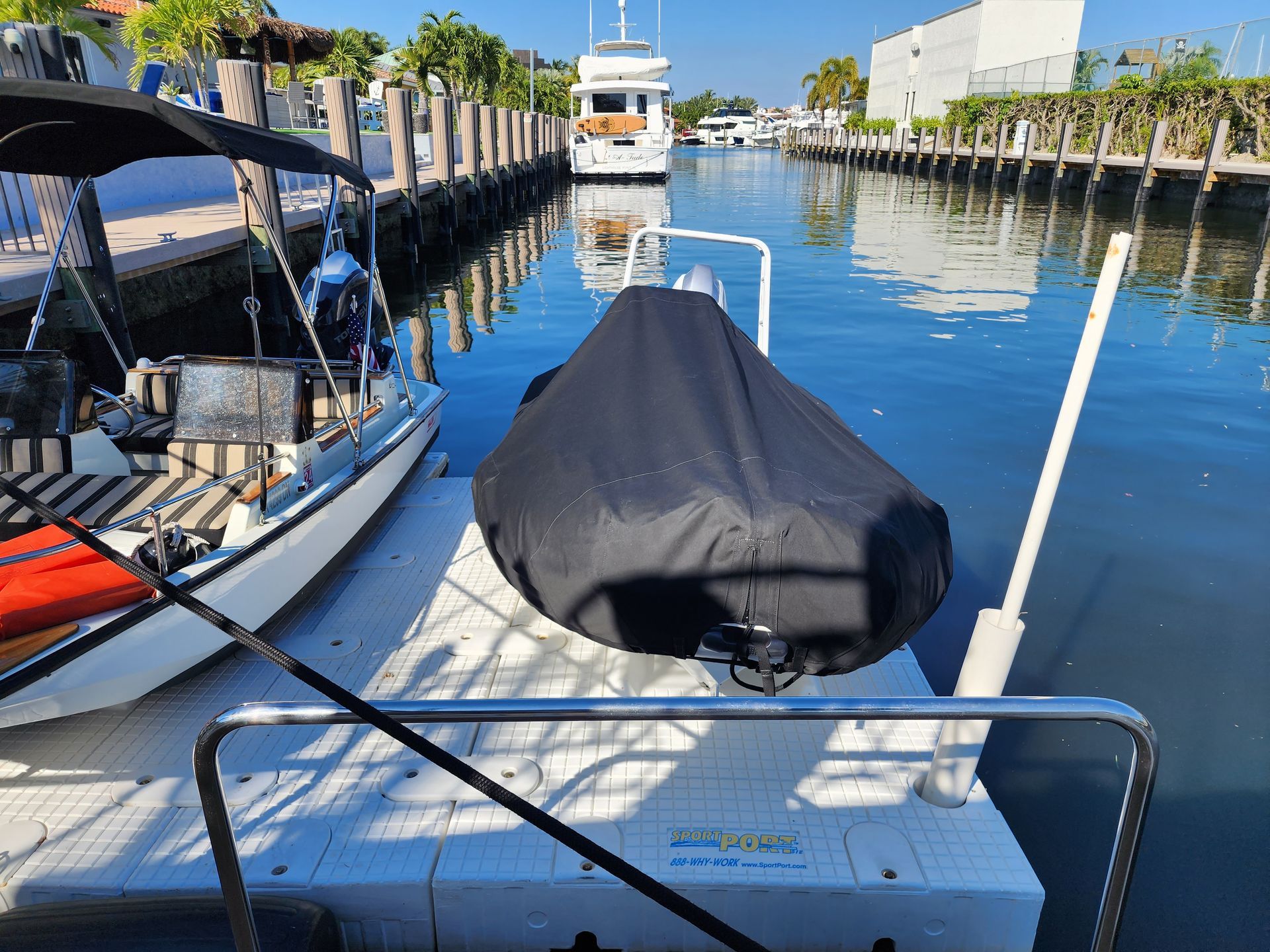 A boat is sitting on a dock with a black cover on it