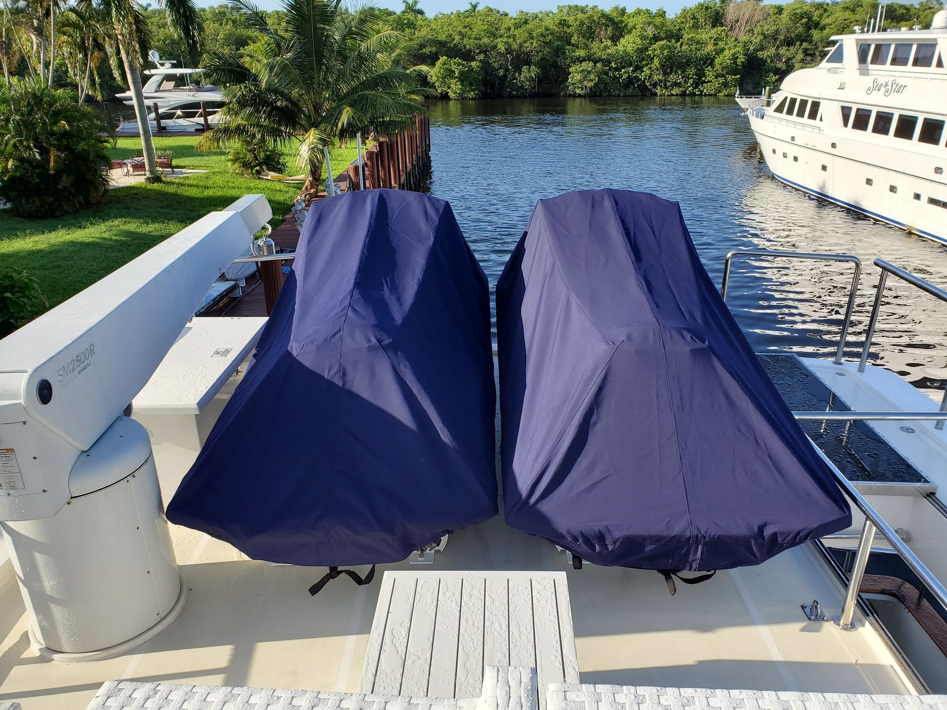 Two boats are covered in blue covers on the deck of a boat.