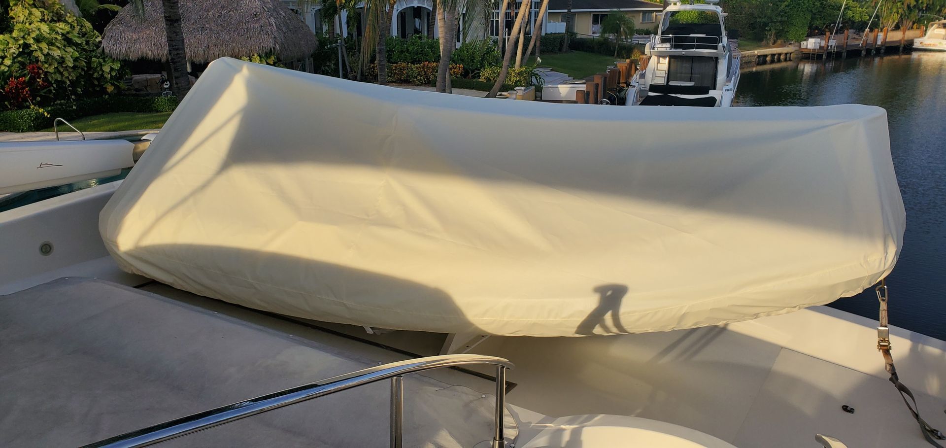 A boat with a white cover on it is sitting in the water.