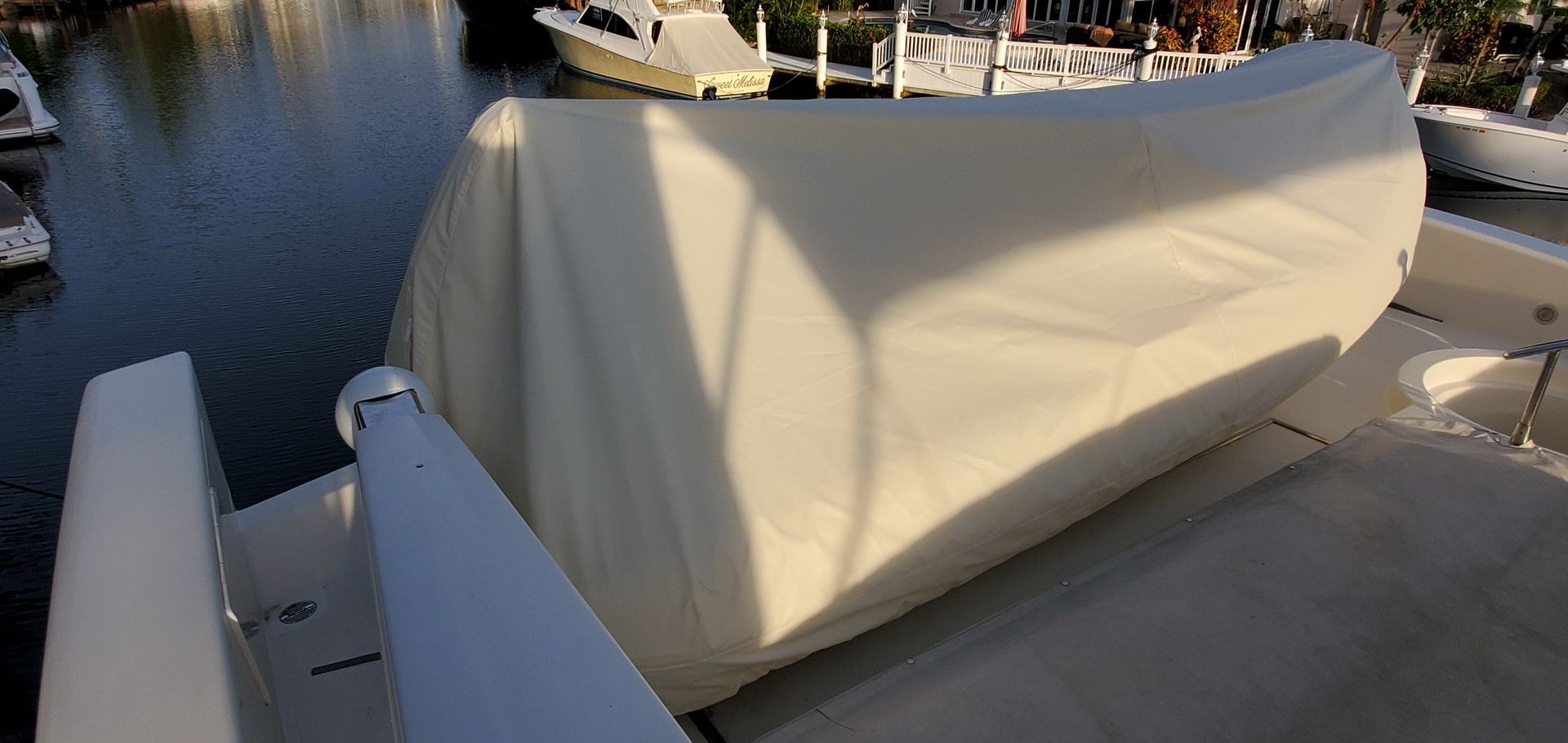 The back of a boat with a white cover on it is sitting in the water.