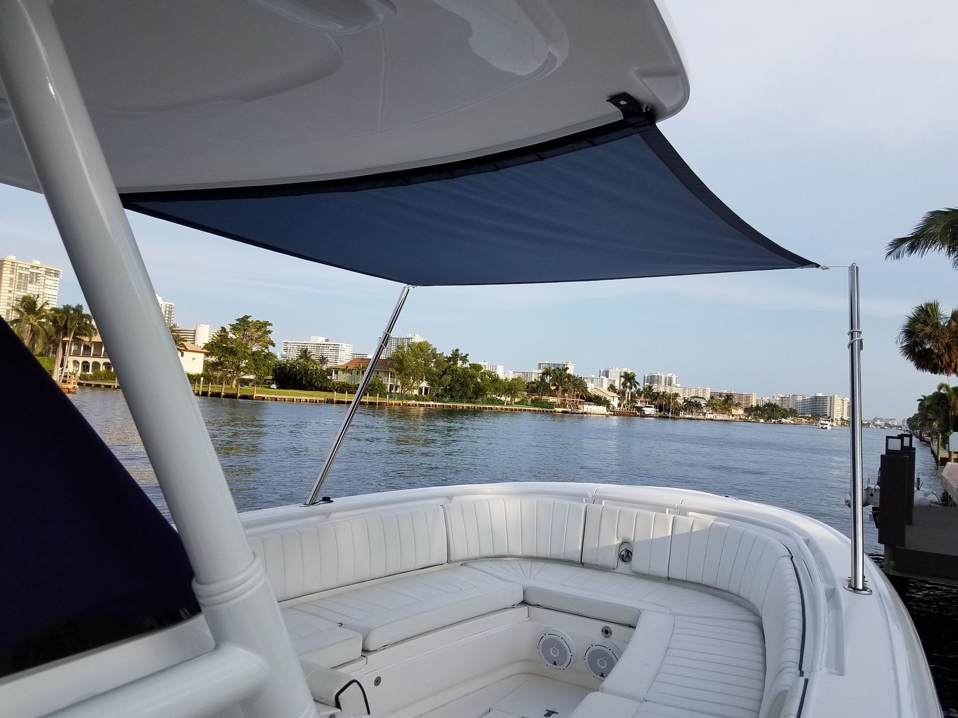 A white boat with a blue umbrella on top of it