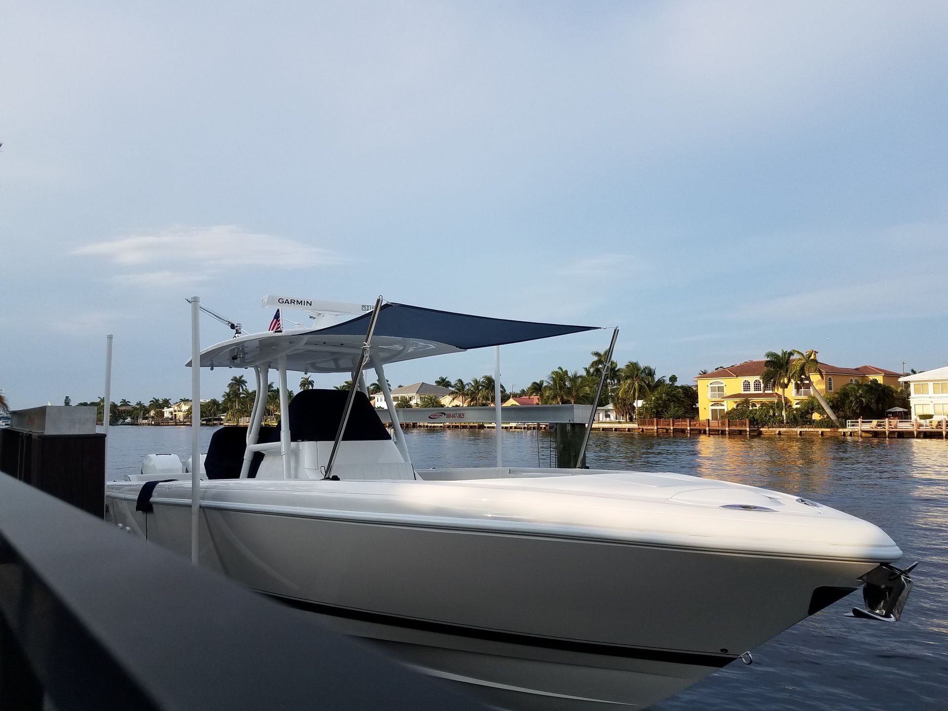 A white boat with a blue canopy is docked at a dock.