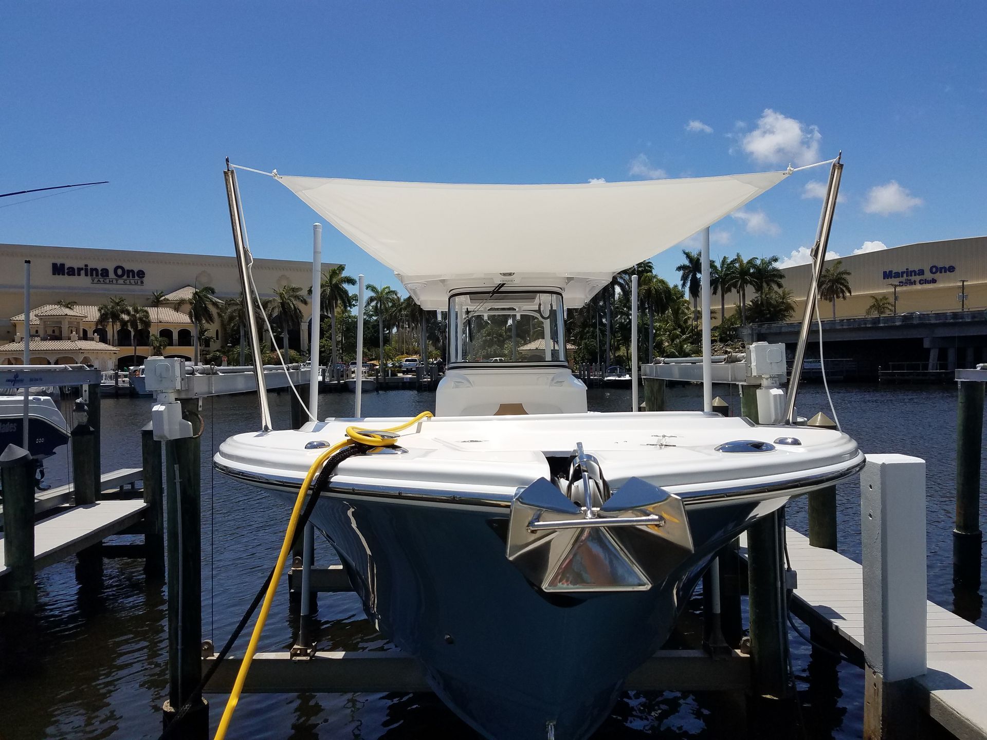 A boat is docked at a dock with a white sail on top.