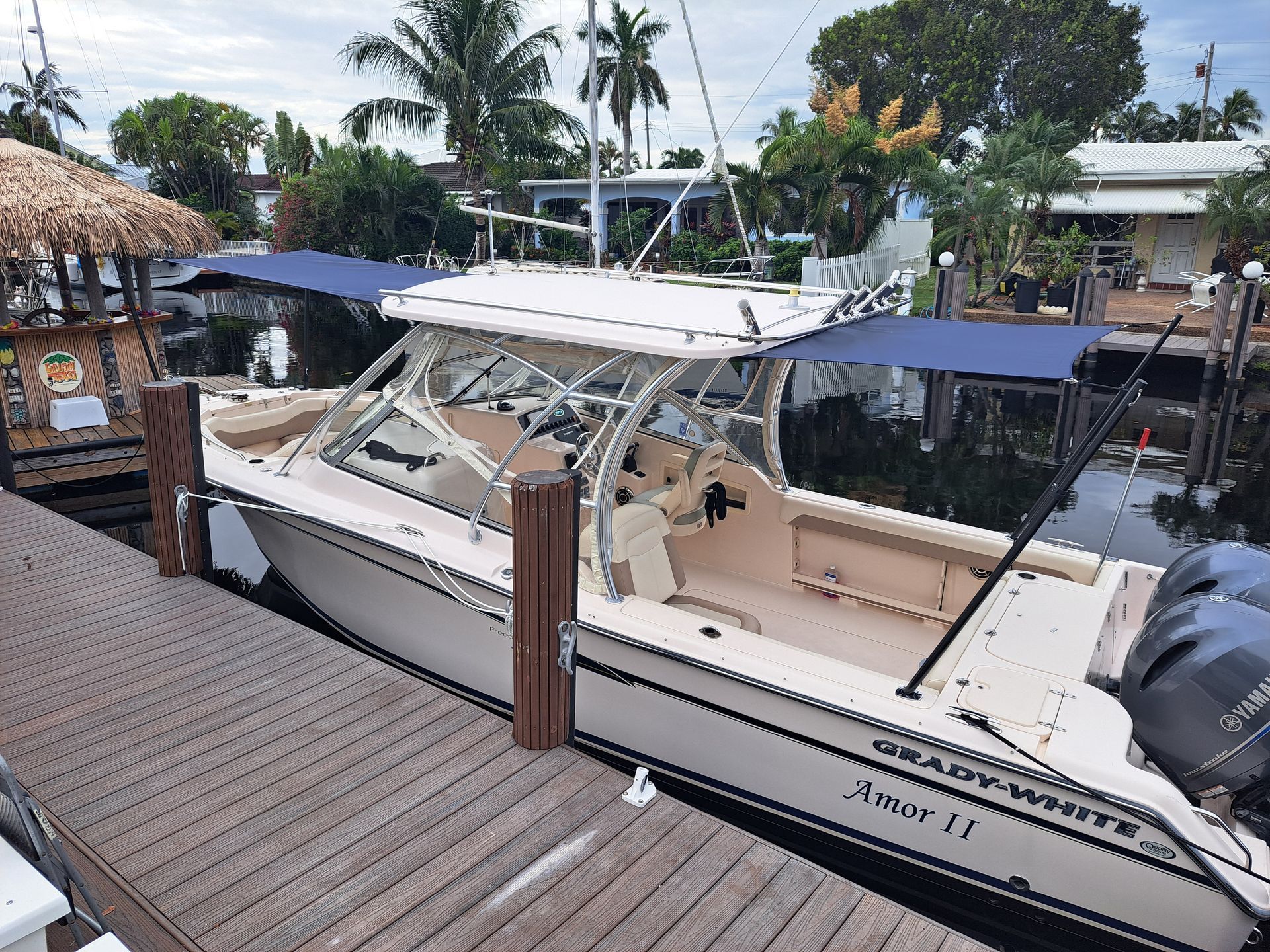 A boat is docked at a dock with a blue umbrella on top of it.