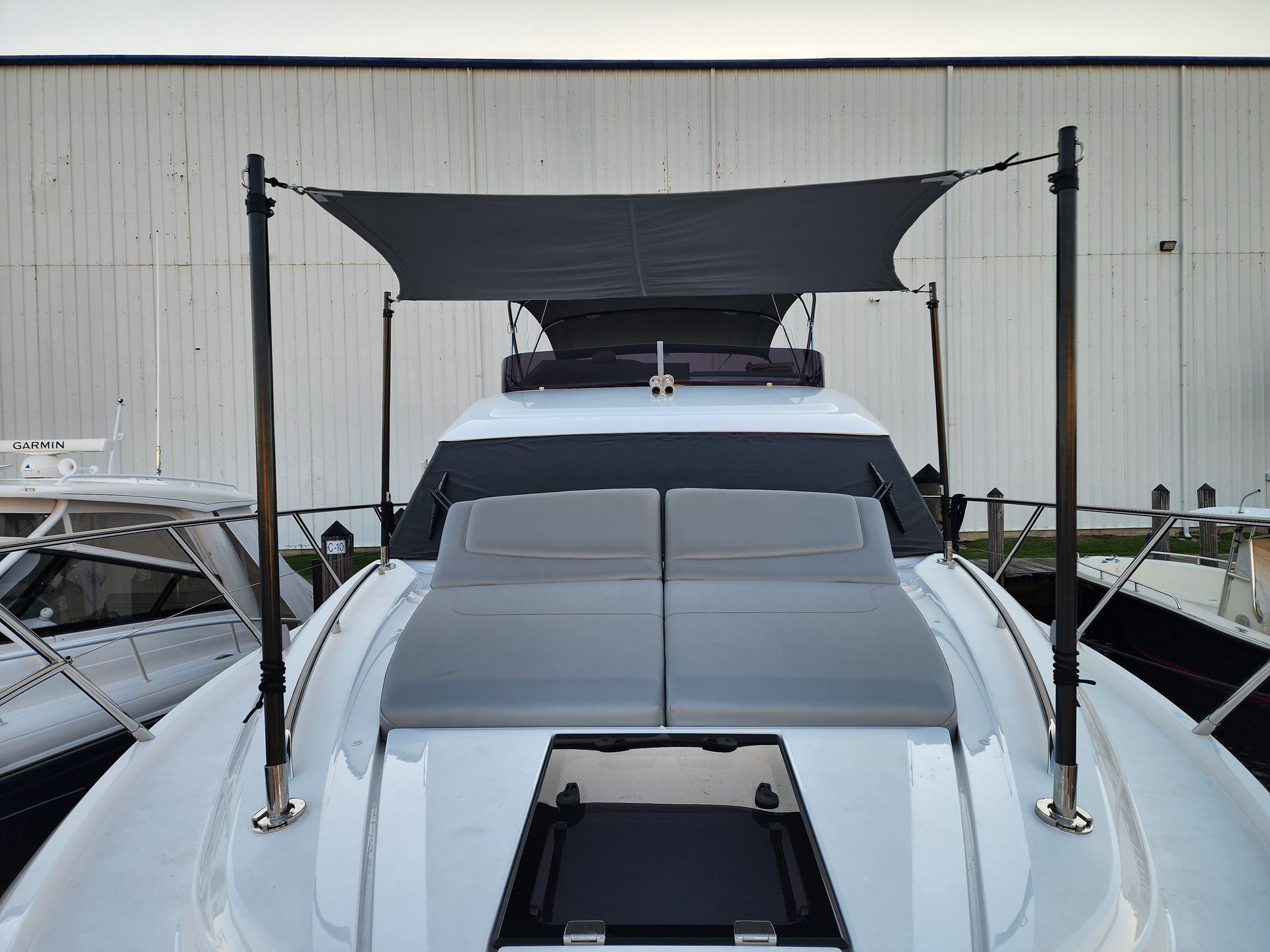 A white boat with a sail on top of it is parked in front of a building.