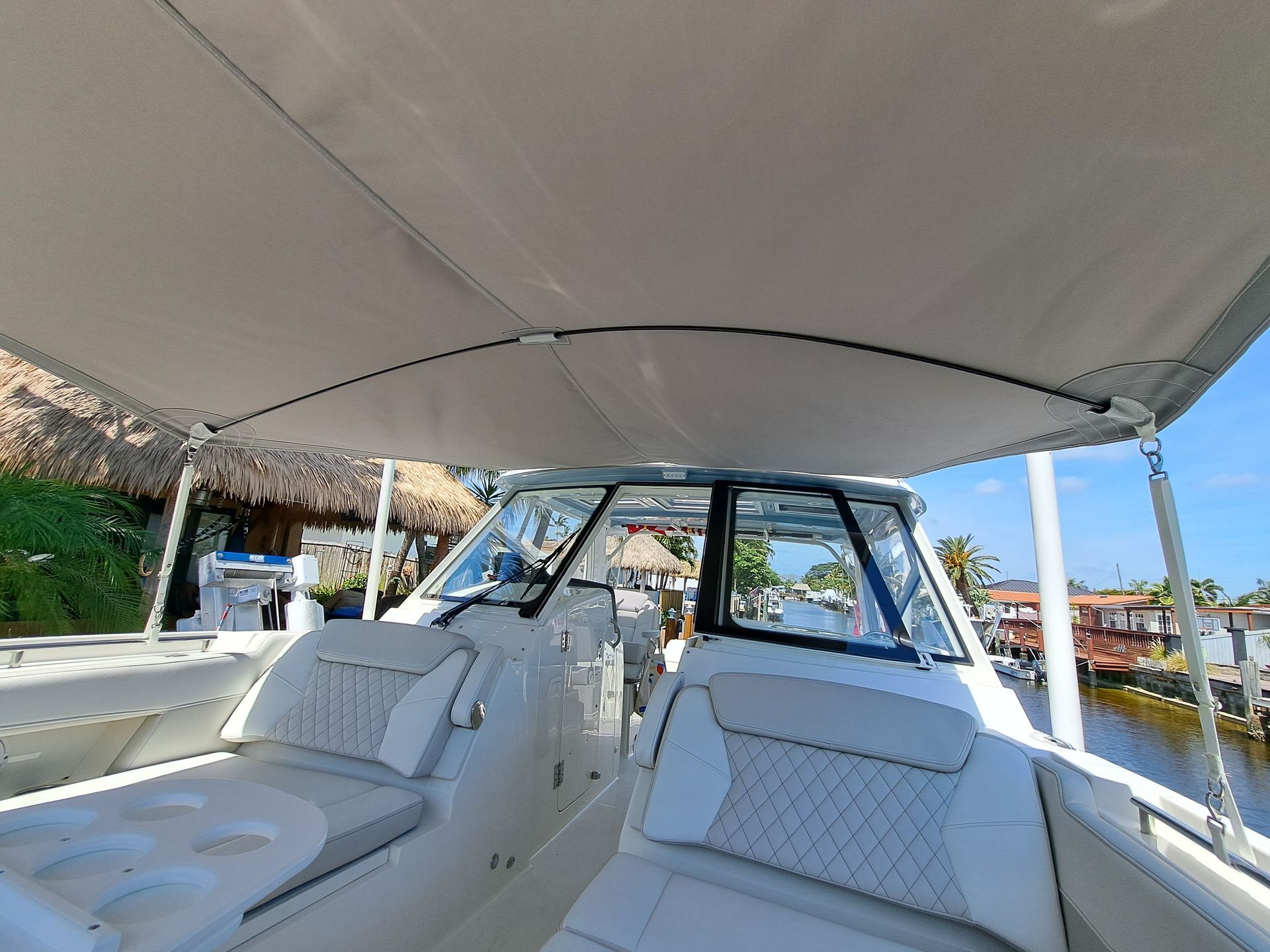 The inside of a boat with white seats and a canopy