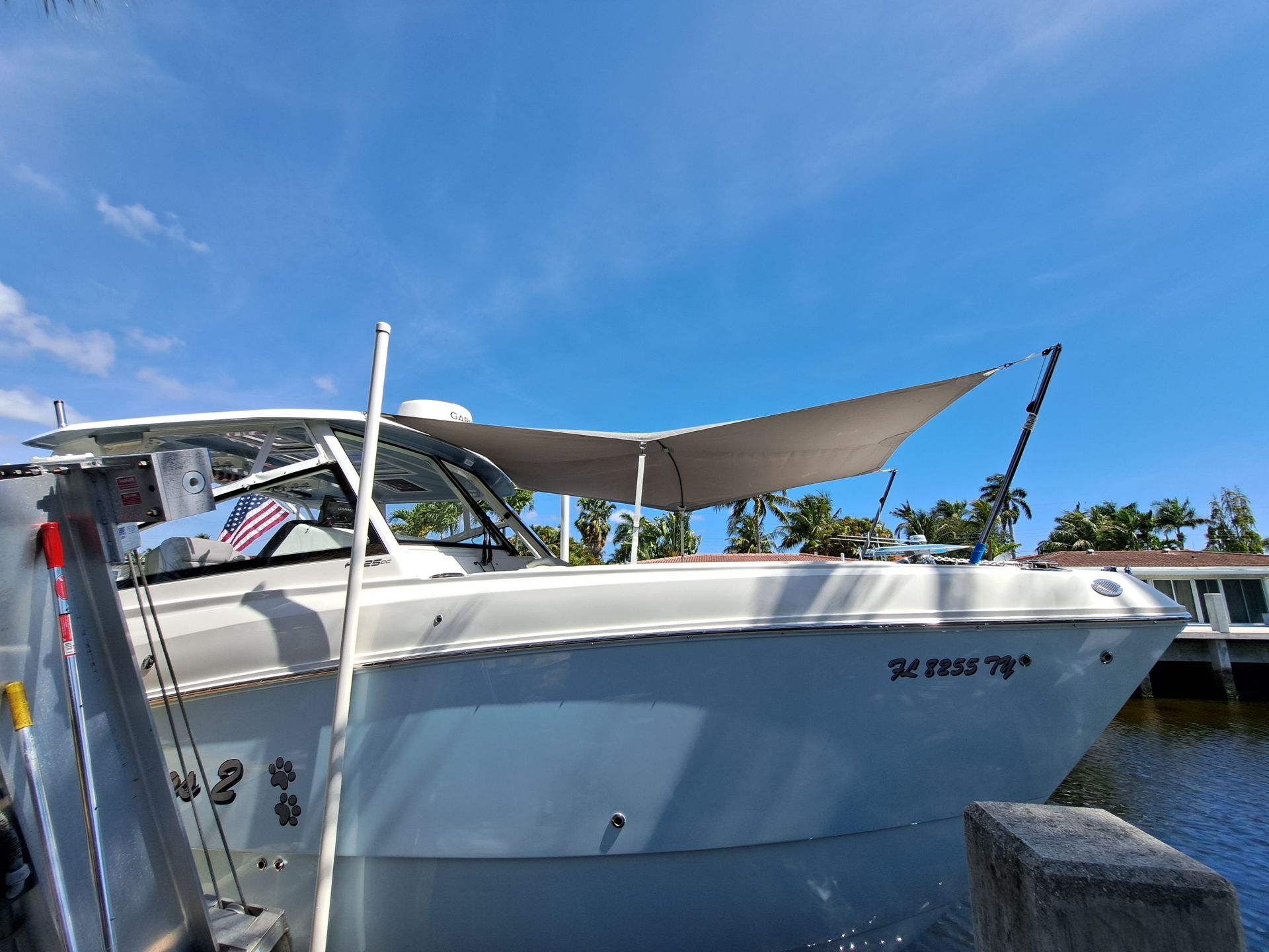 A white boat with a canopy on top of it is docked at a dock.