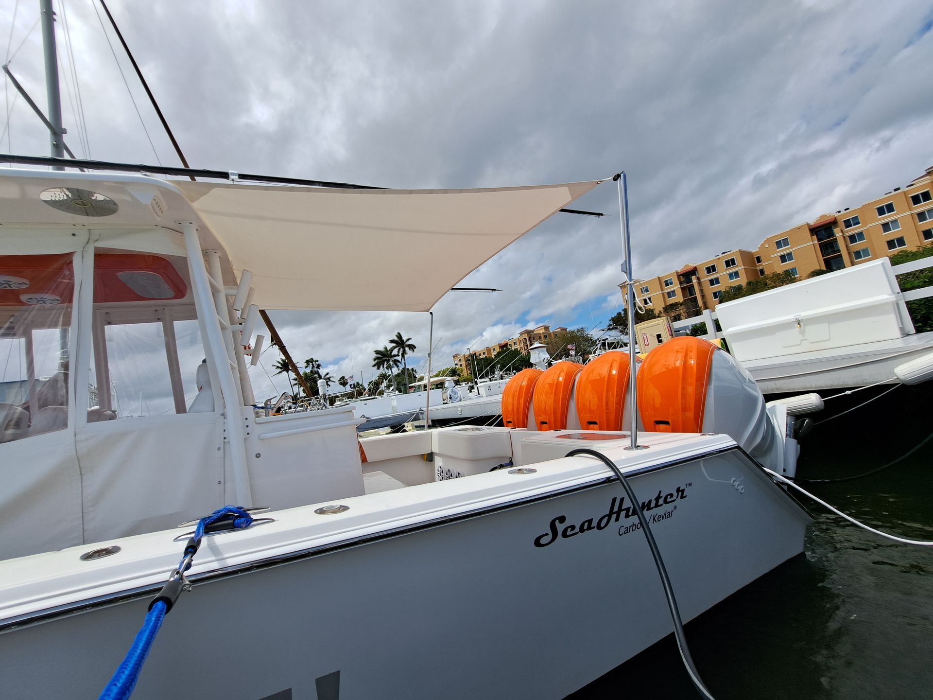 A white boat with a sail is docked in a marina.