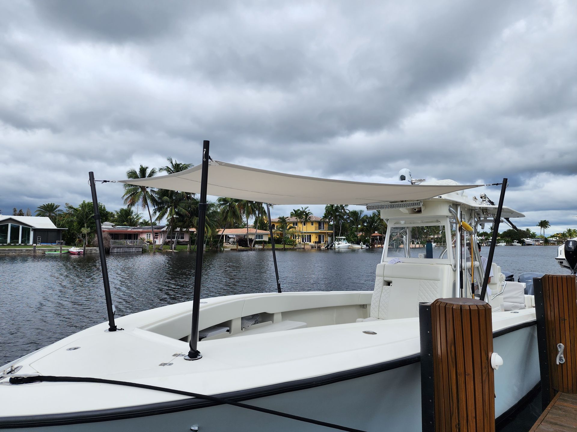 A white boat is docked at a dock with a canopy on top of it.