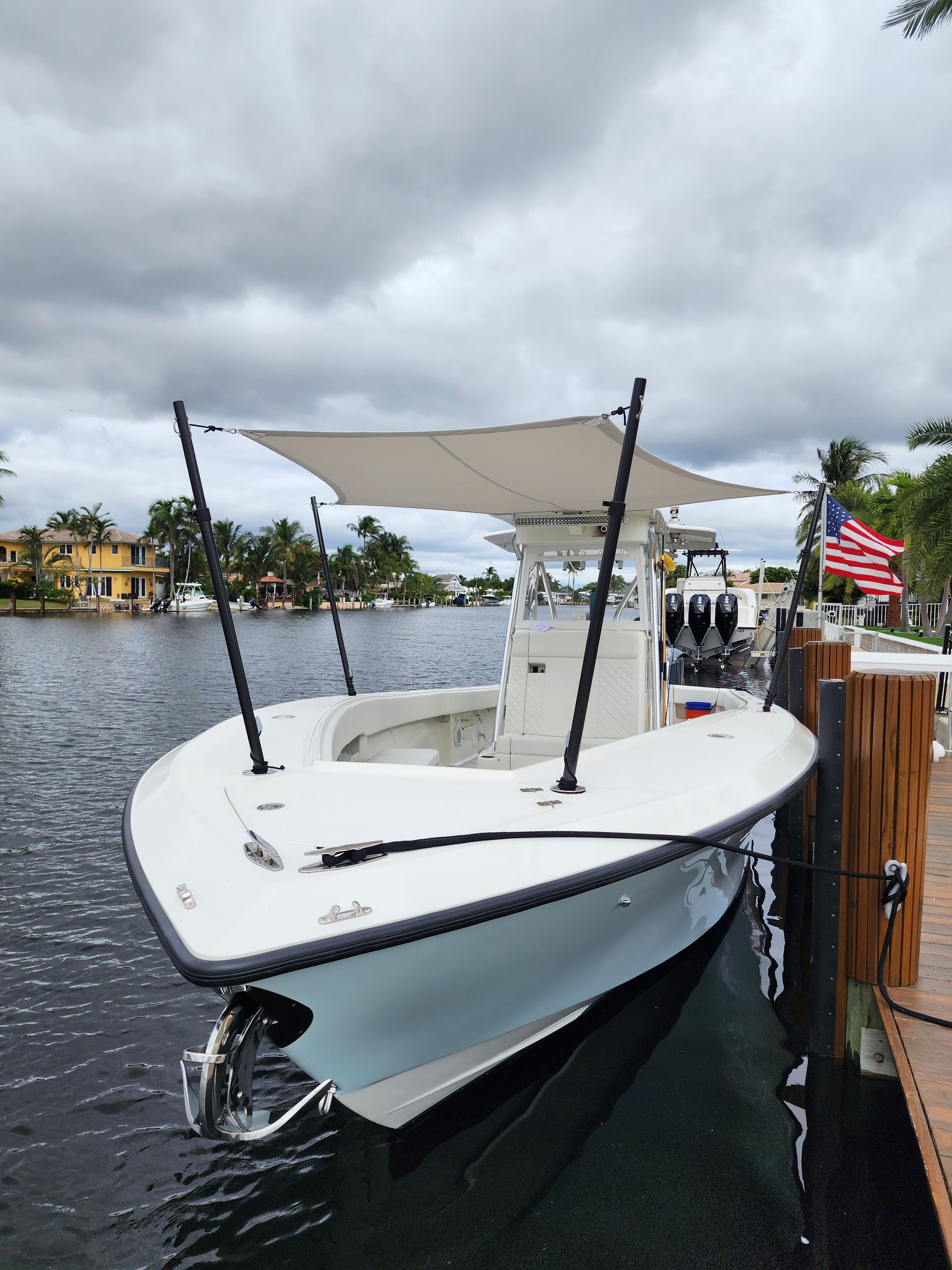 A white boat with a canopy is docked at a dock