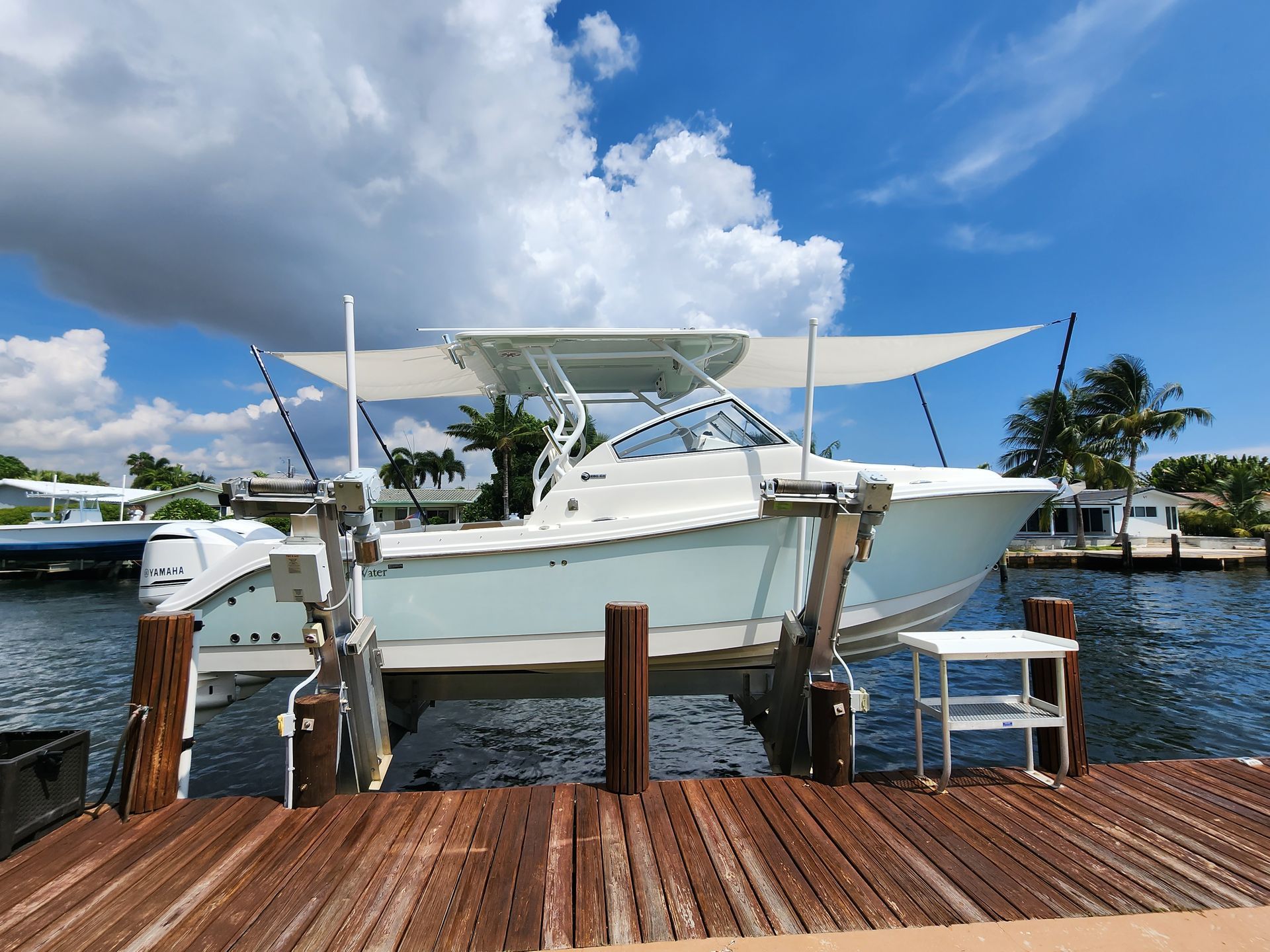 A white boat is docked at a dock on a cloudy day.