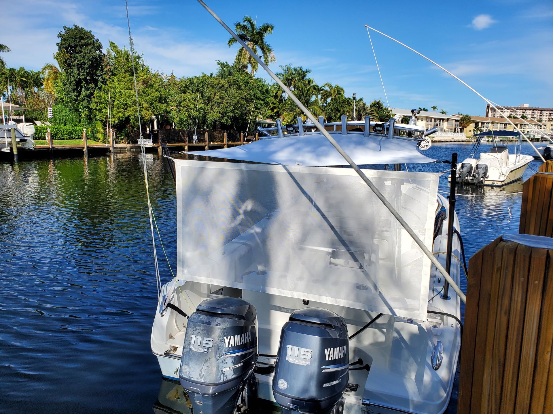 A white boat with two engines is docked in the water.