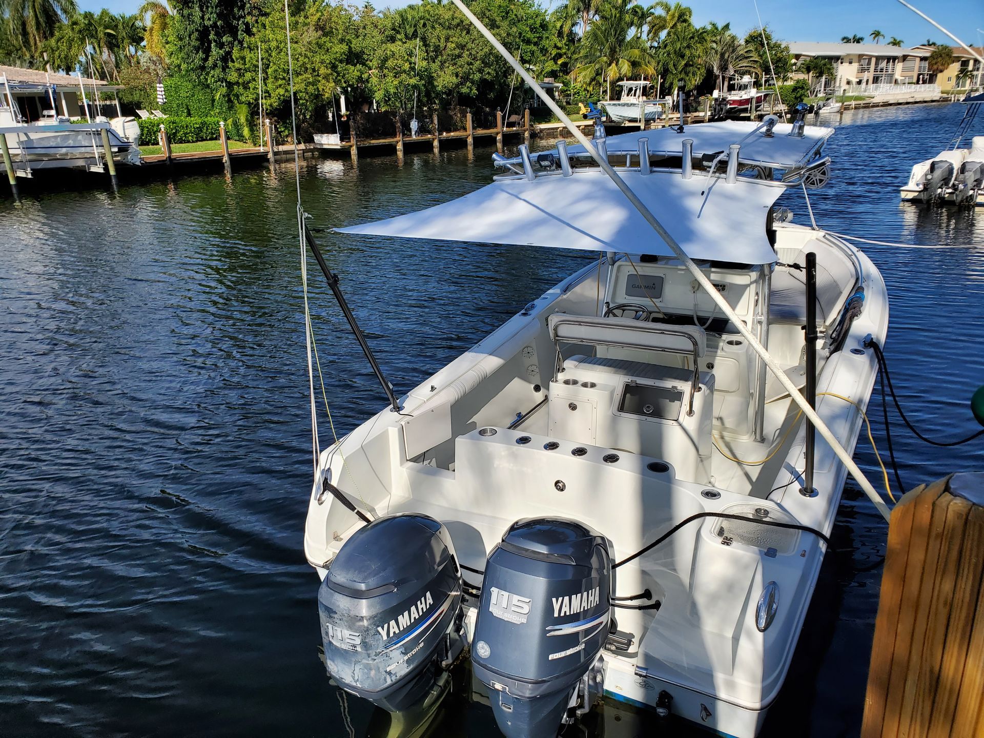 A white boat with two engines is docked in the water.