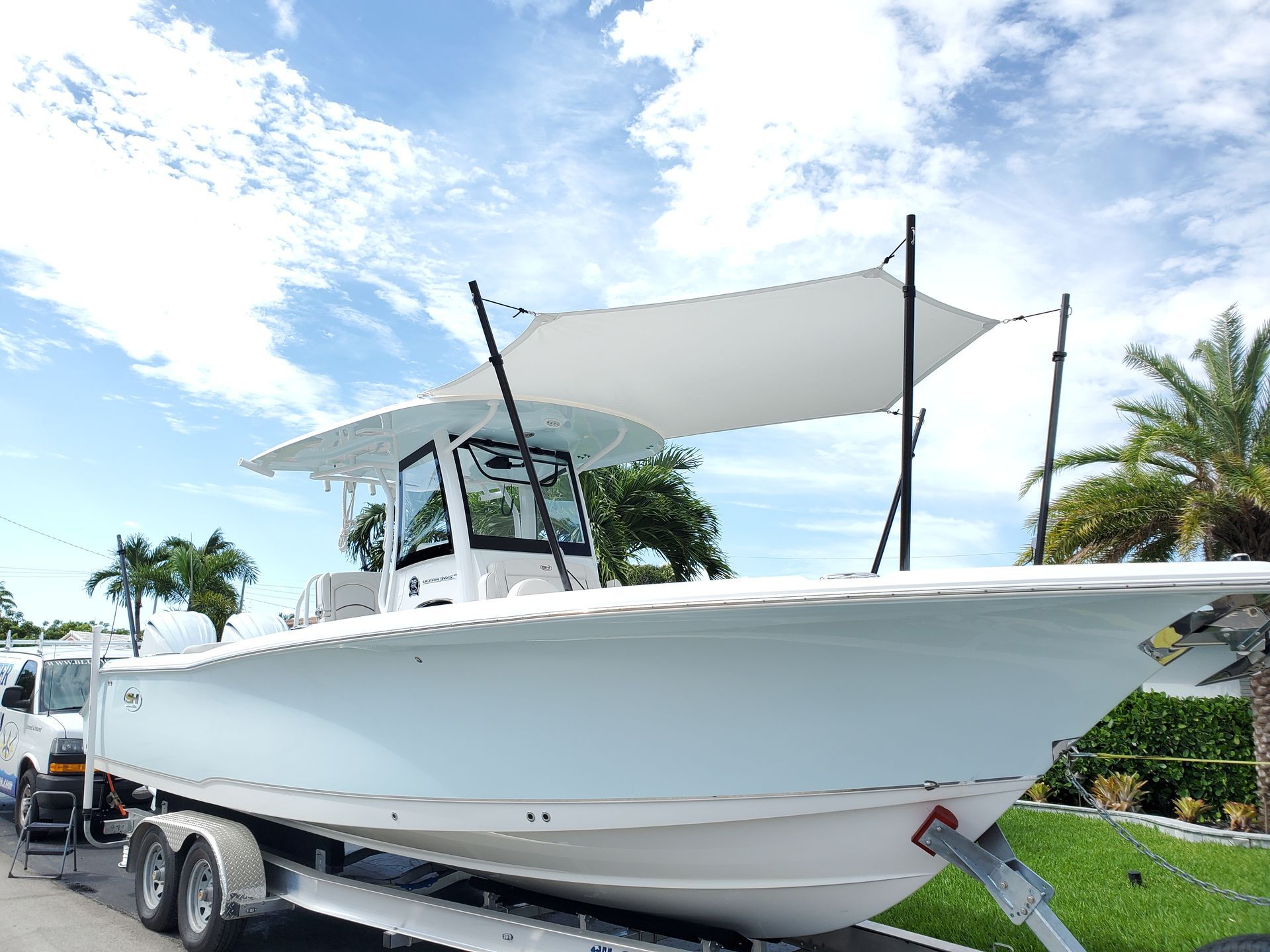 A white boat with a canopy is parked on a trailer.