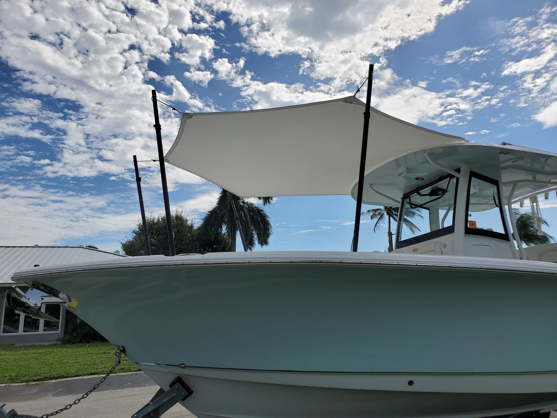 A boat with a canopy on top of it is parked in front of a house.