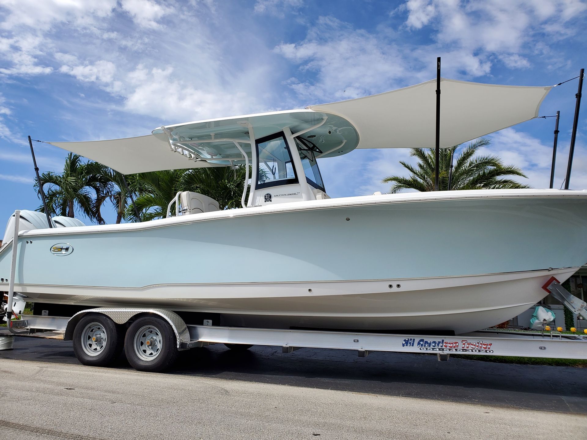 A boat is parked on the side of the road on a trailer.