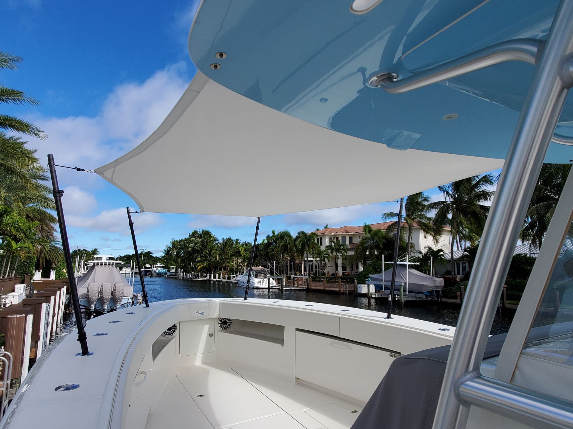 A white boat with a blue sky and palm trees in the background